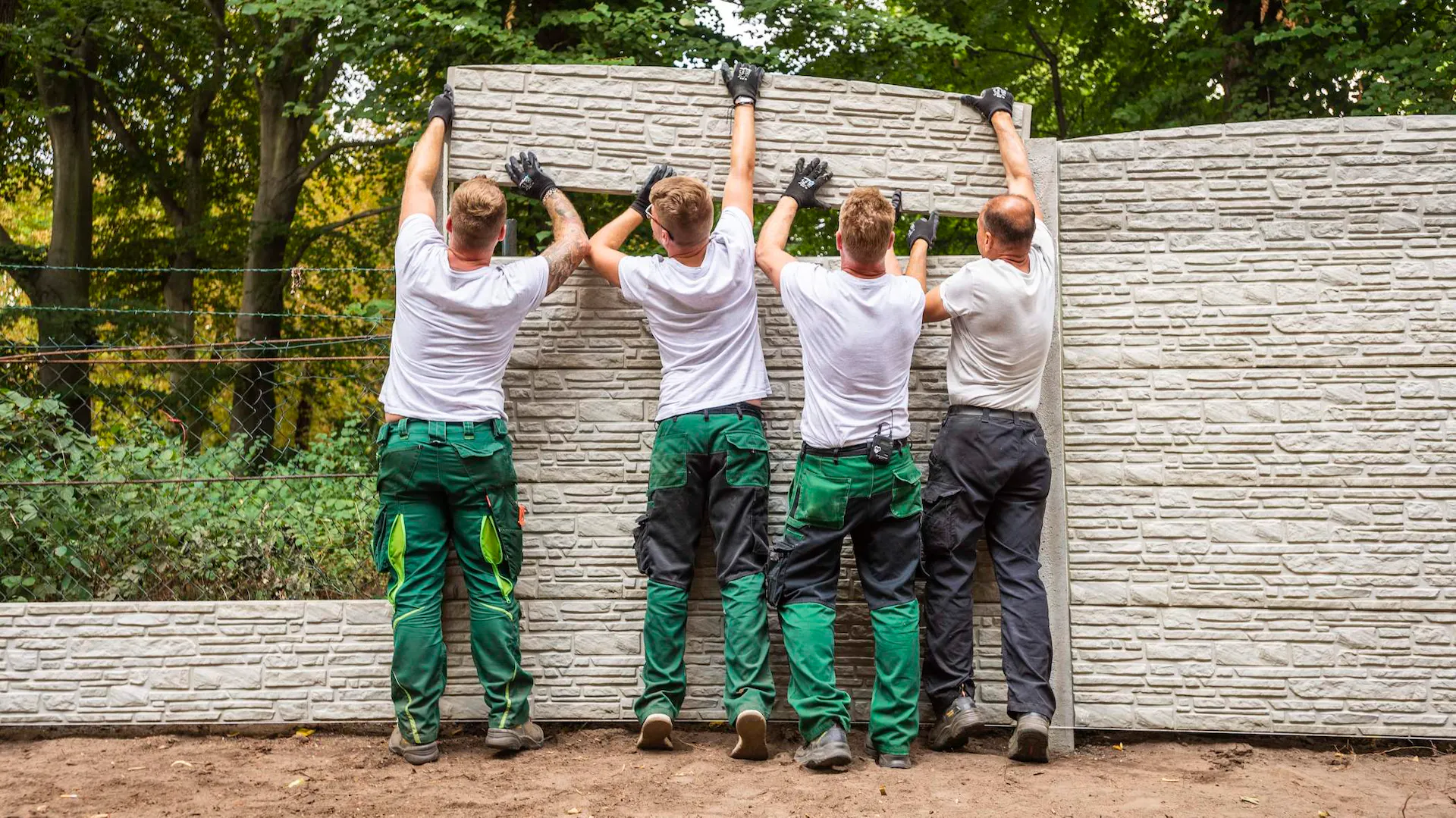 Handwerker bringen Mauer-Element an.