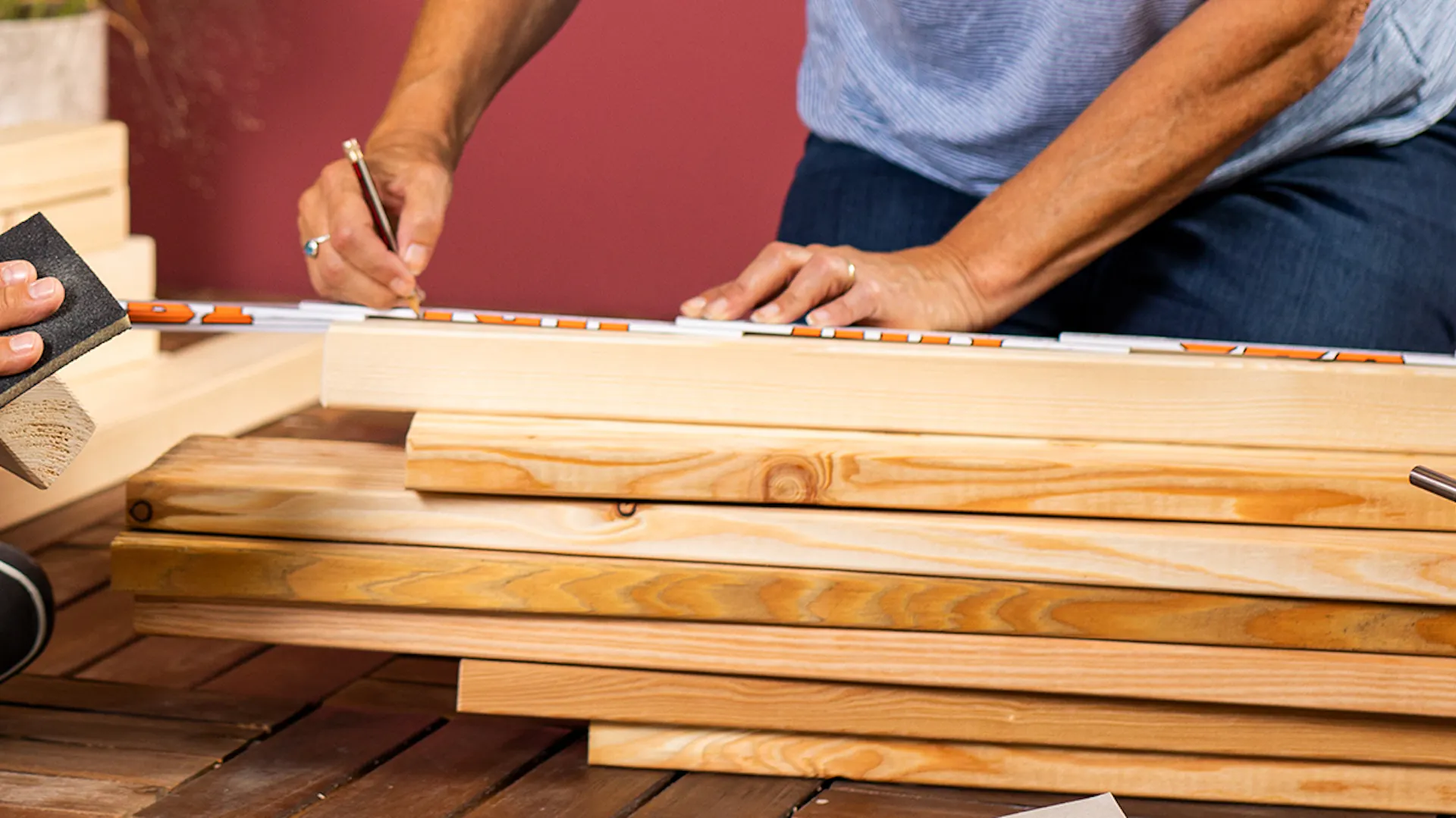 Una persona misura dei listelli di legno per la costruzione di una panca