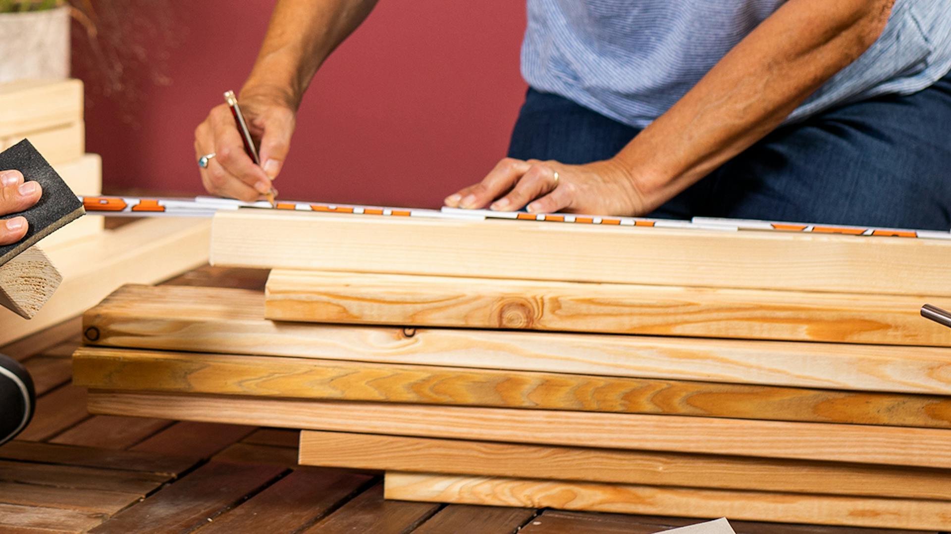 Una persona misura dei listelli di legno per la costruzione di una panca