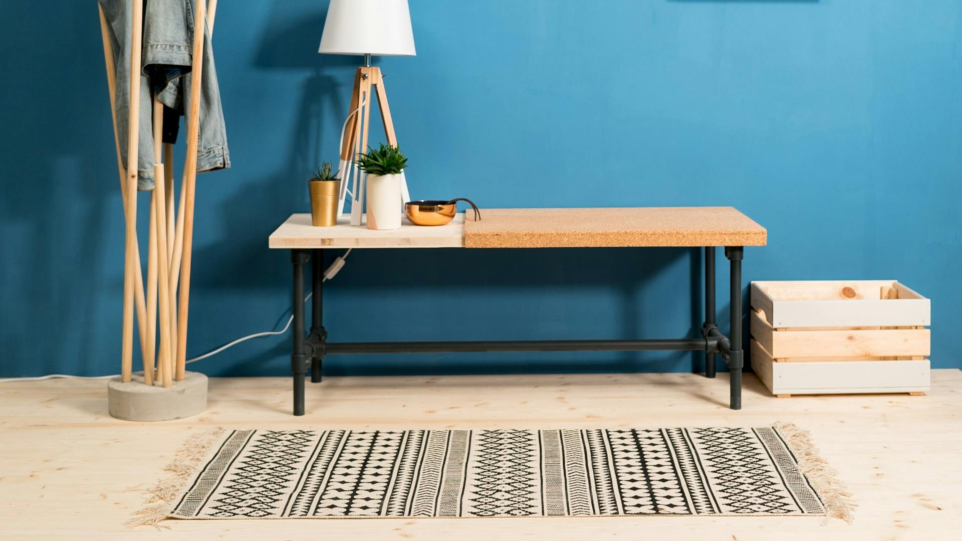 Panca con gambe di tubolari in una stanza, davanti ad una parete blu accanto ad un guardaroba dietro a un tappeto