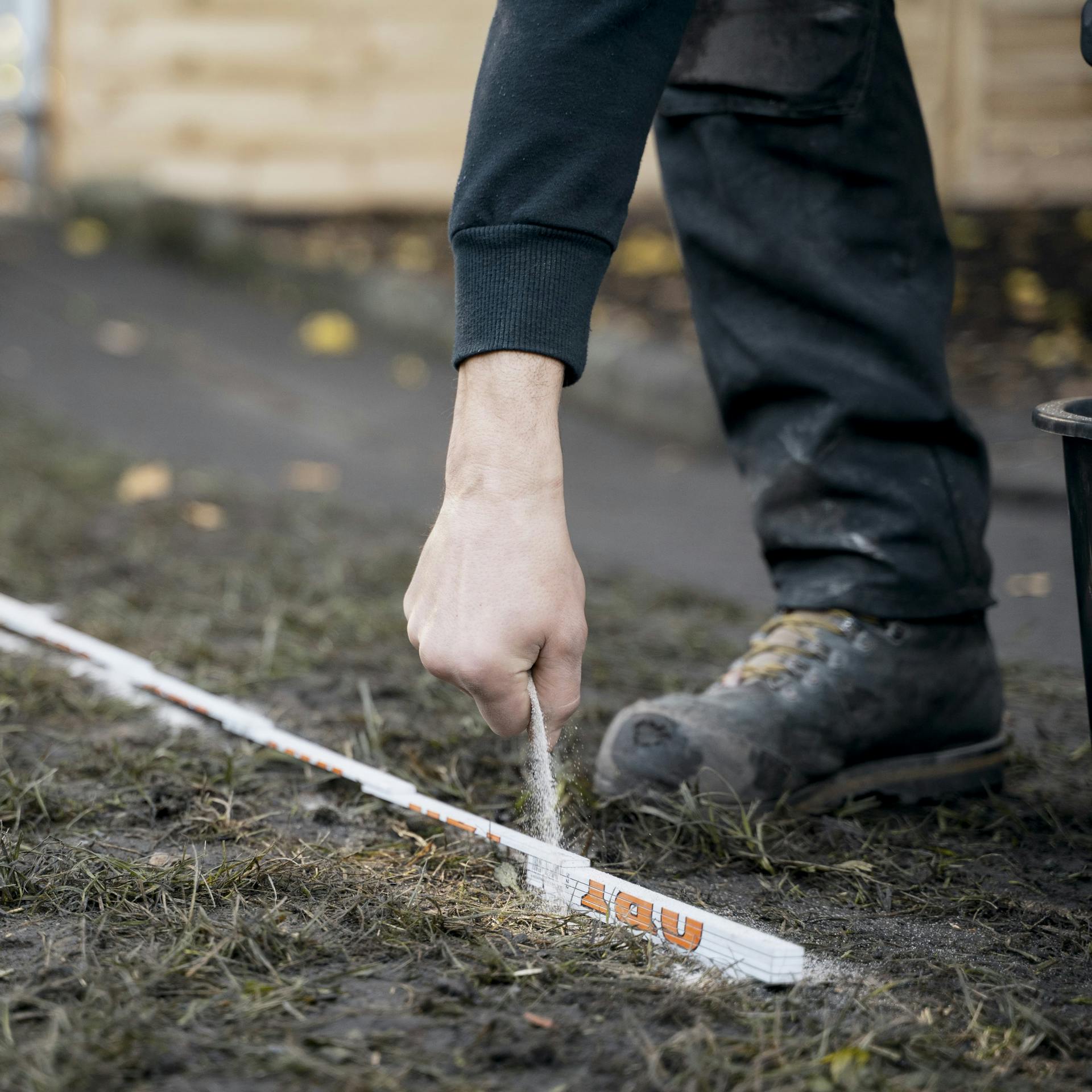 Heimwerker markiert eine Fläche im Garten mit Feinsand.