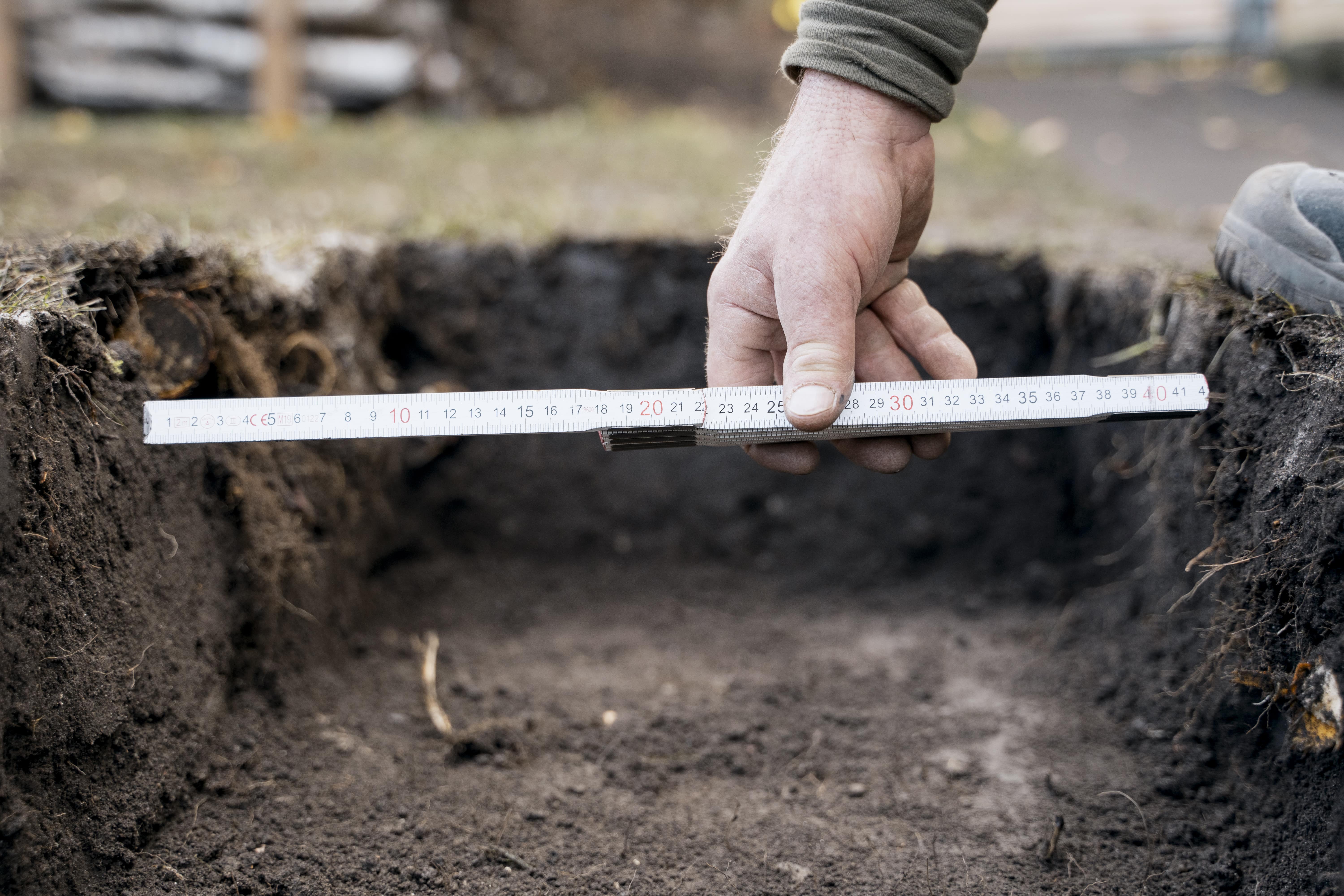 Gödör mérése a kertben.