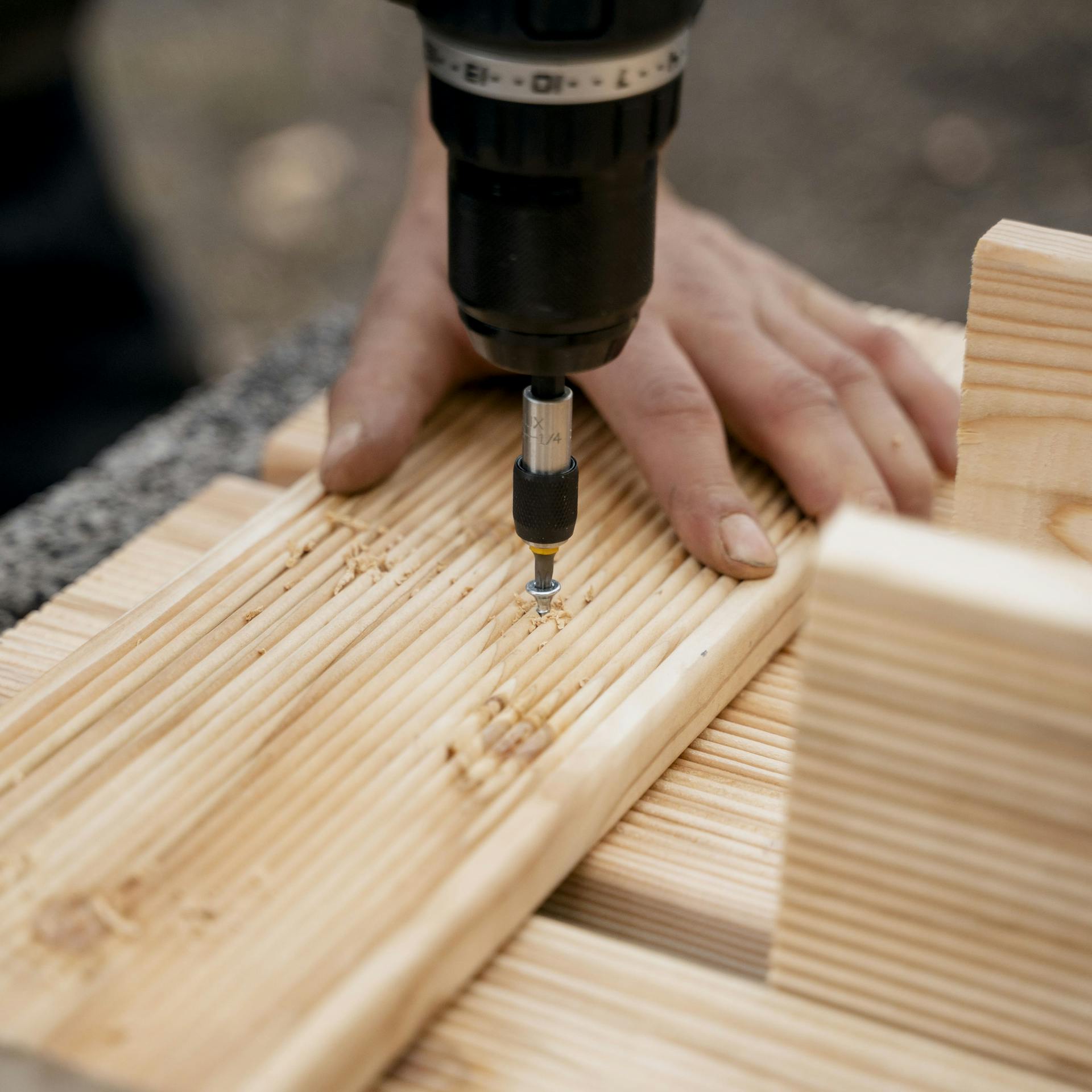 Heimwerker verschraubt Holzdielen und Pflanzsteine miteinander.