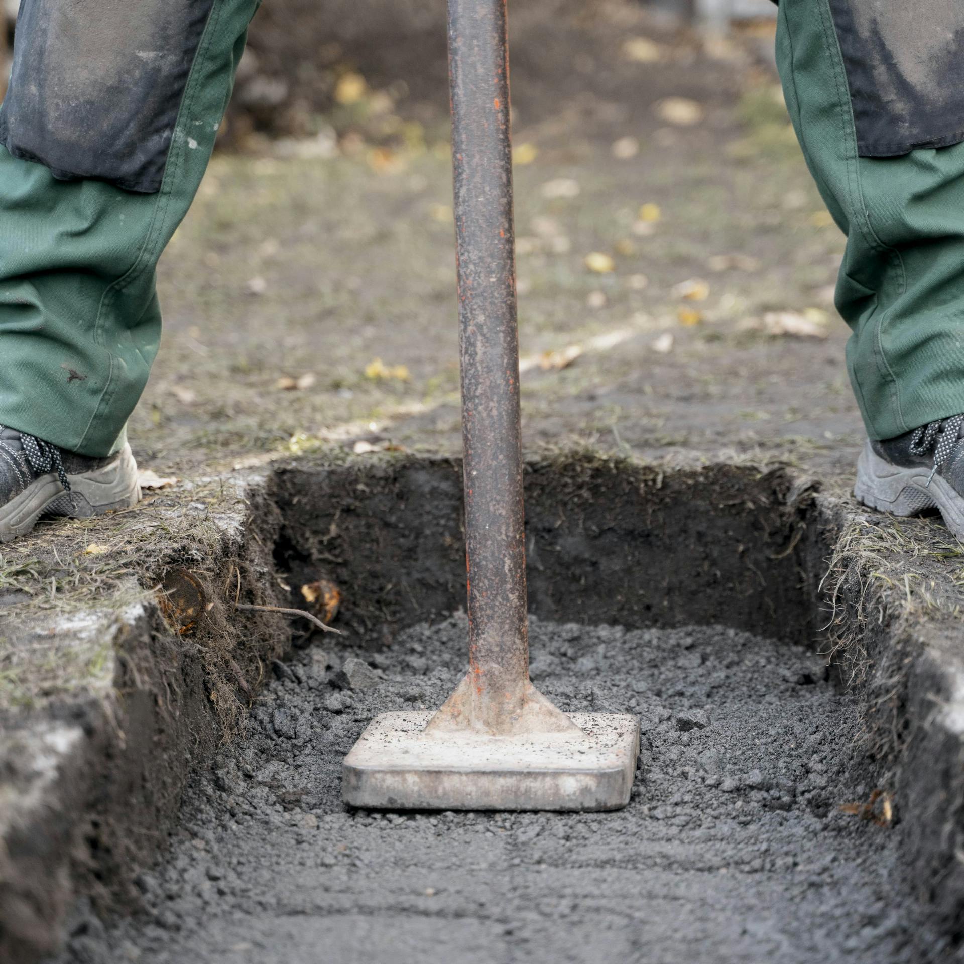 Heimwerker verdichtet Tragschicht mit einem Handstampfer.