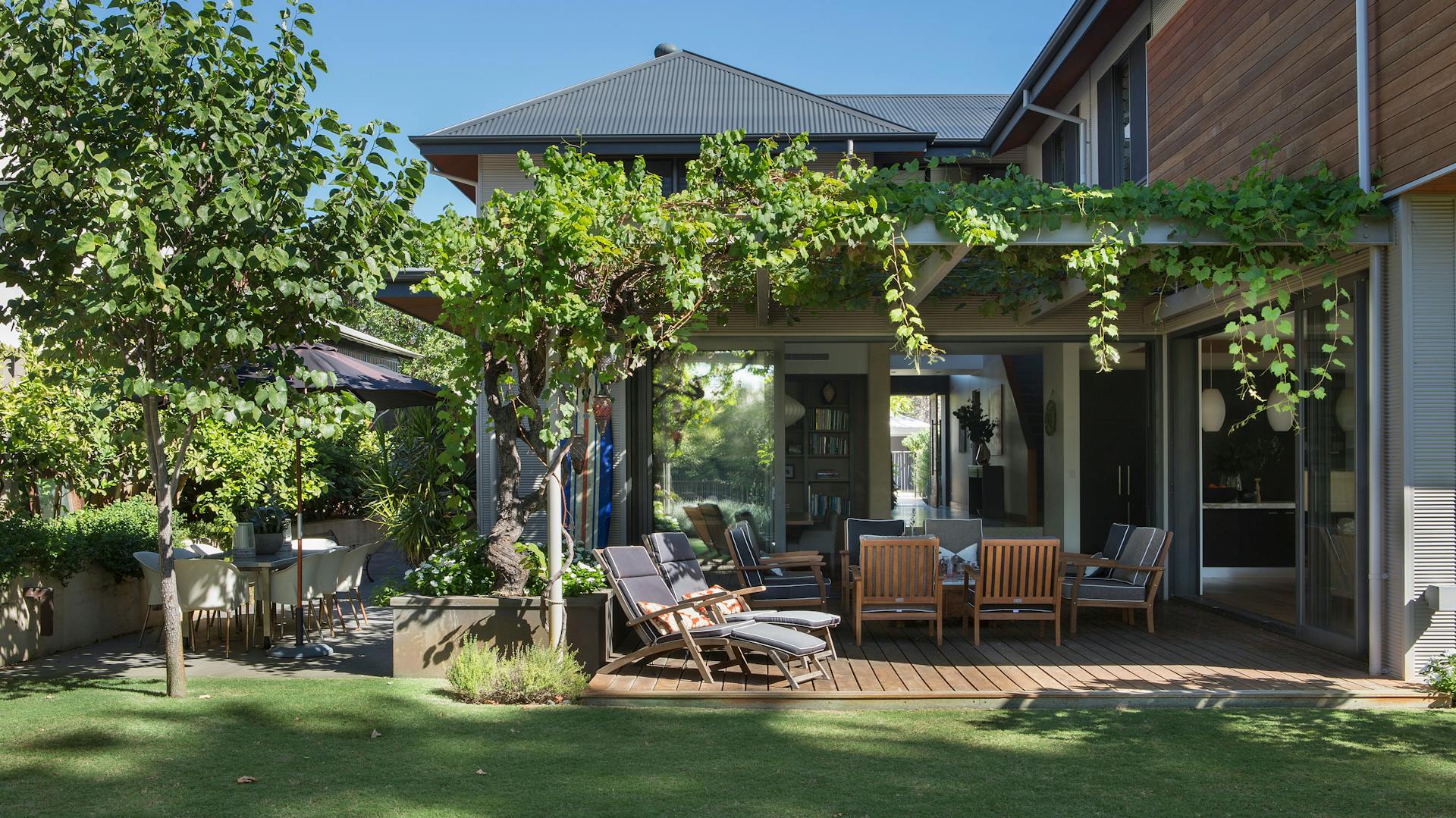 Terasz zöldellő pergolával és kerti bútorokkal