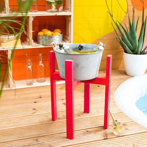 Die selbstgemachte Getränkekühlung steht auf einer Holzterrasse, auf welcher ein Pool eingesetzt worden ist und daneben die Pool Weinkisten platziert sind.