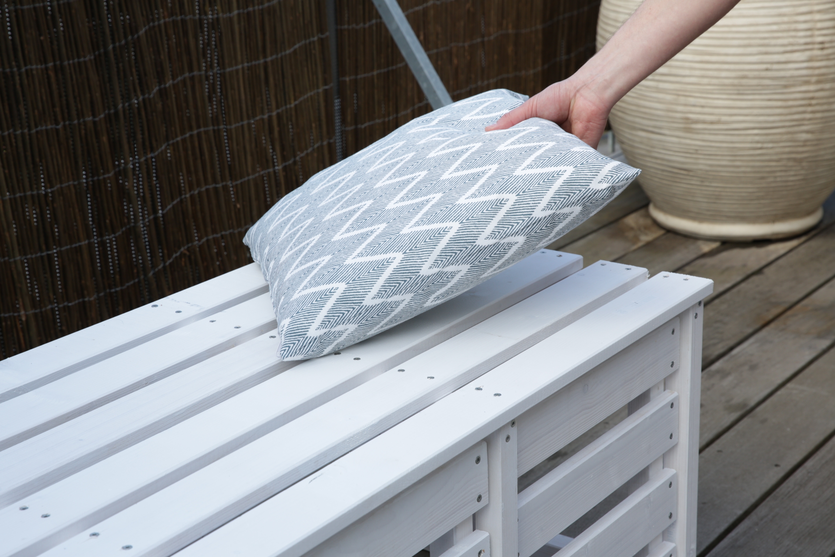 Ruka položí vonkajší vankúš na lavičku