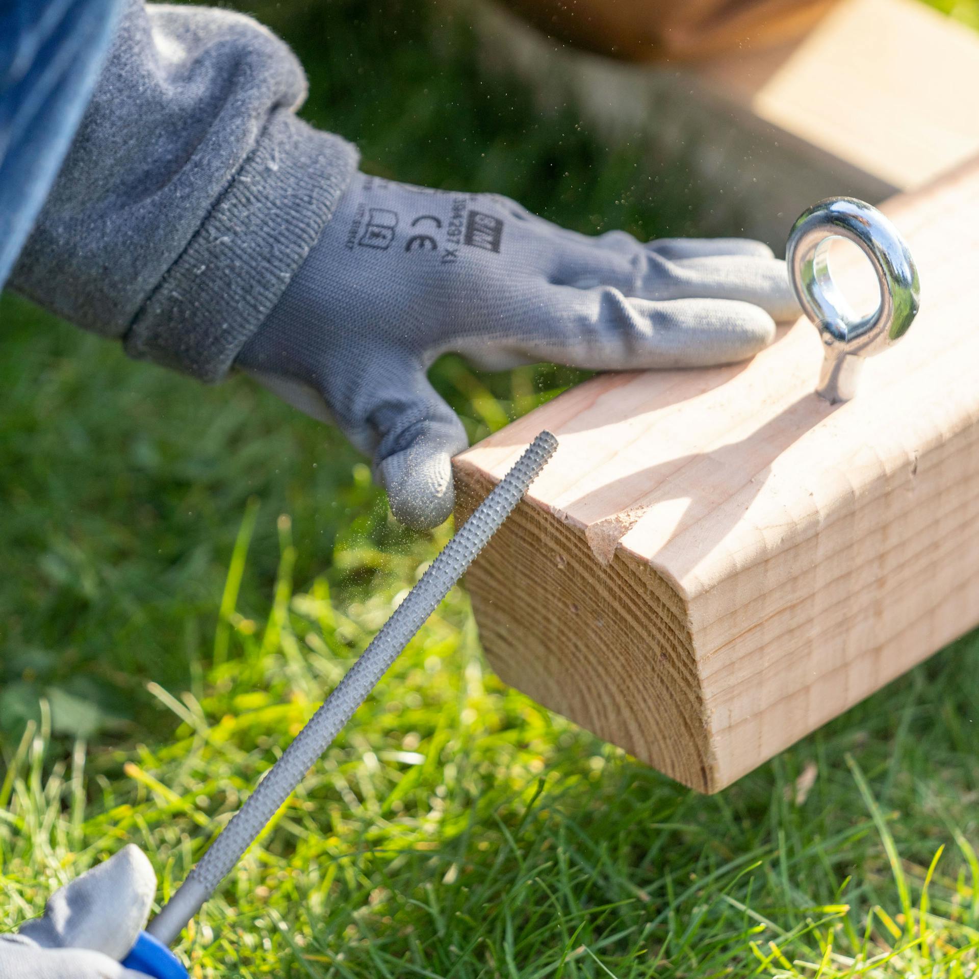 Eine Person feilt an einem Holzbalken