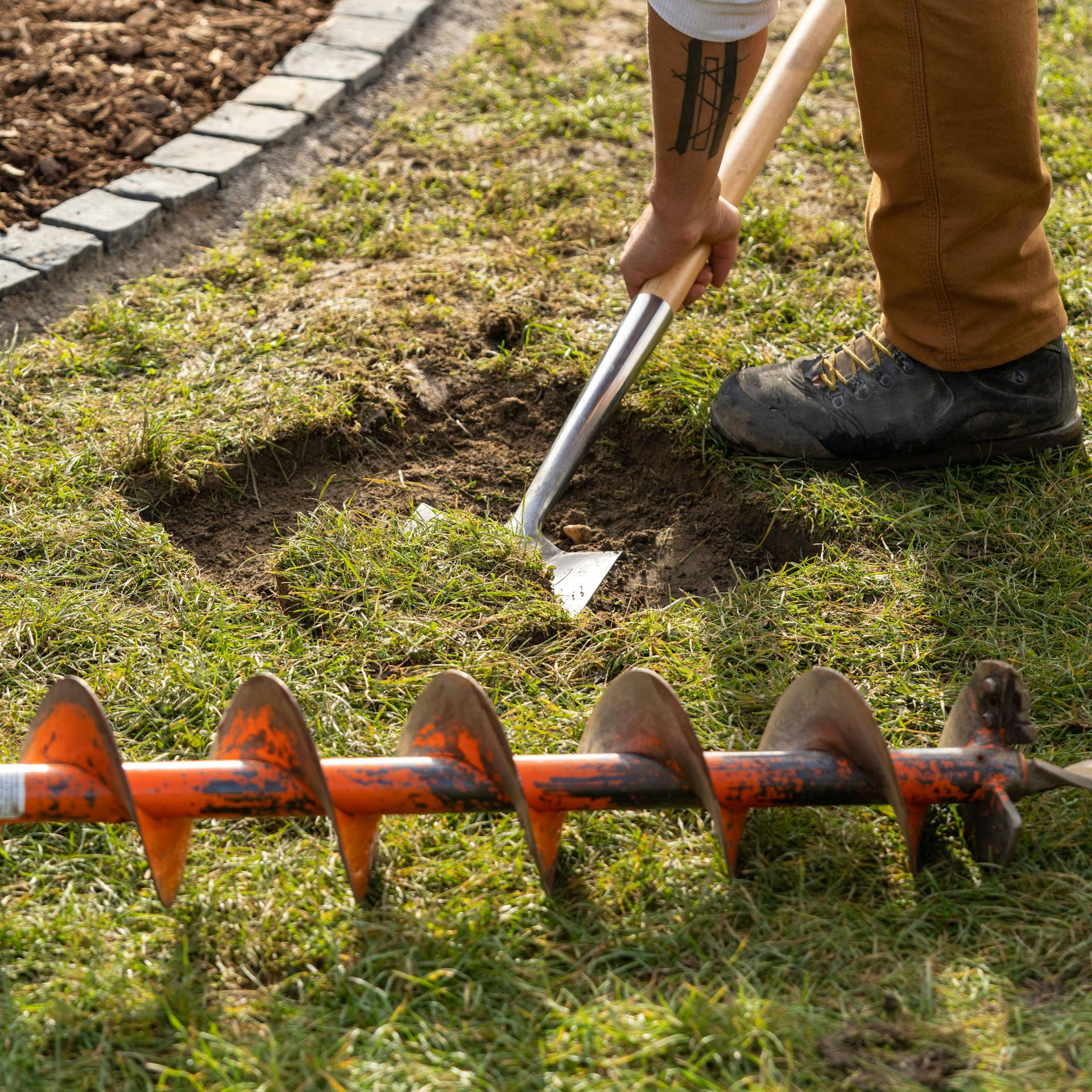 Ein Mann trägt die Grasnarbe mit einem Spaten ab.