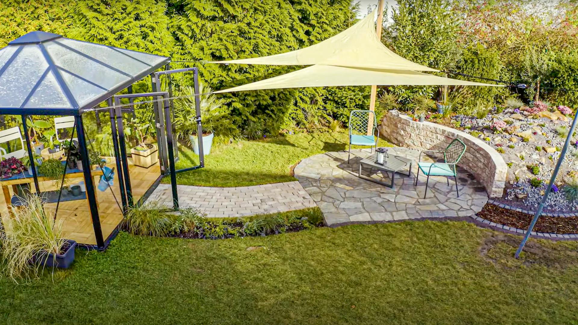 Ein Sonnensegel ist über einer Sitzgruppe im Garten befestigt.