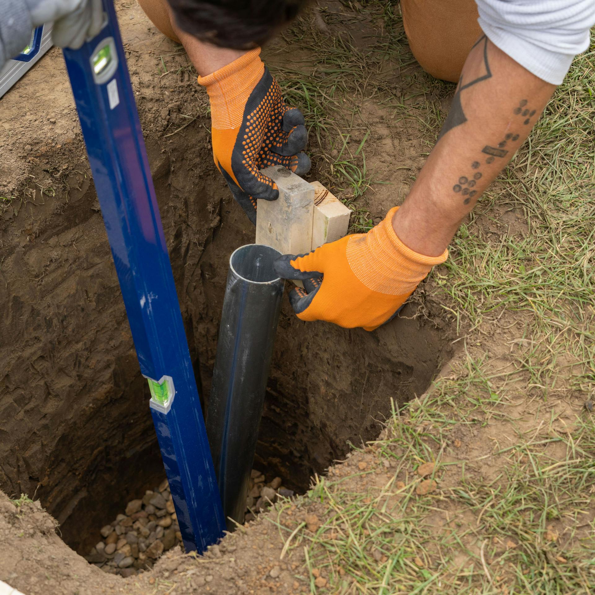 Bodenhülse wird in Erdloch mit einem Holzstück positioniert