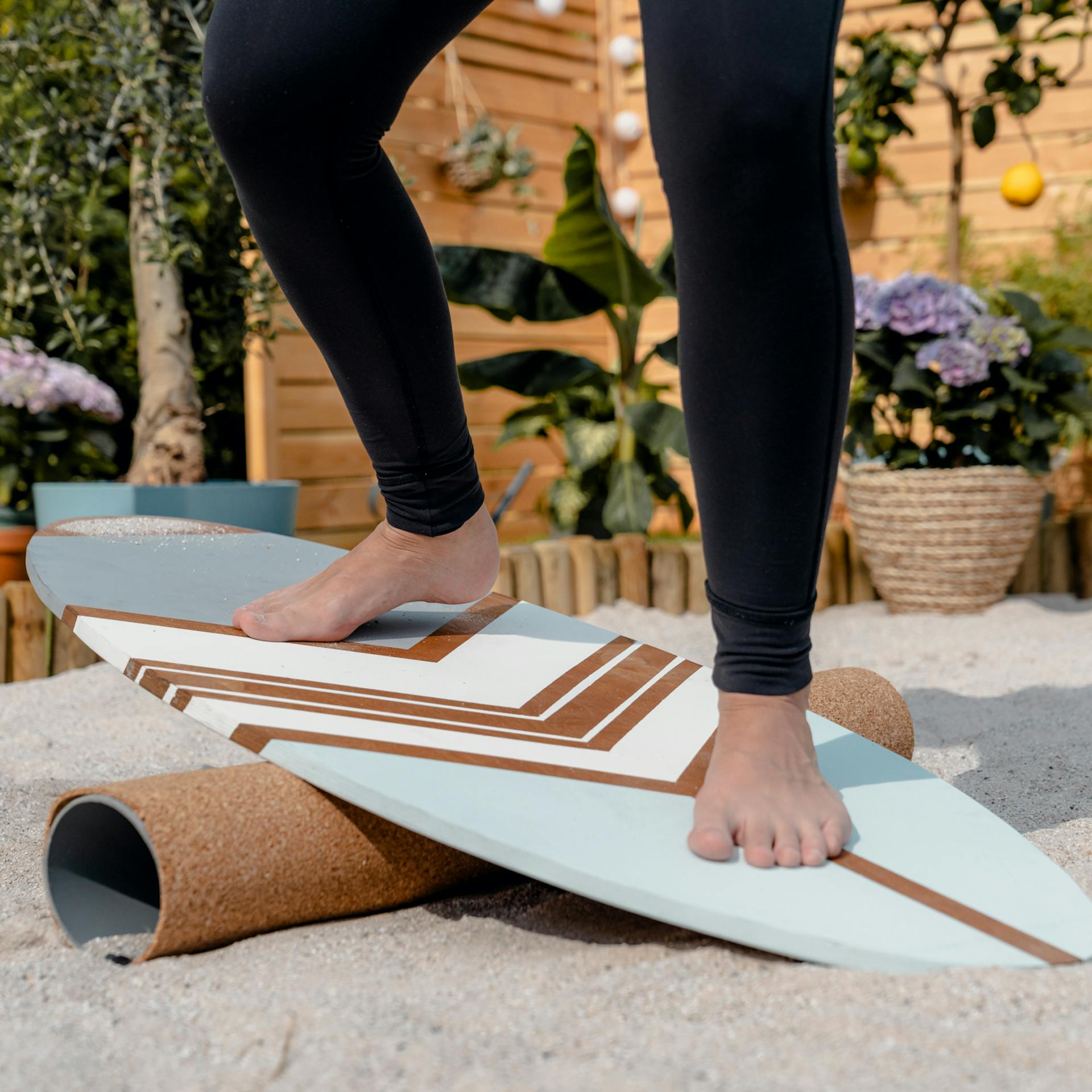 Frau balanciert im Sand auf Balance Board.