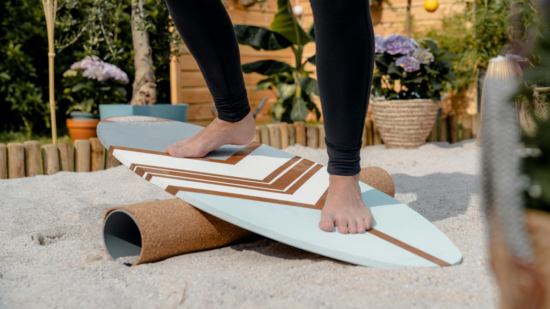 Frau balanciert im Sand auf selbst gebautem Balance Board.