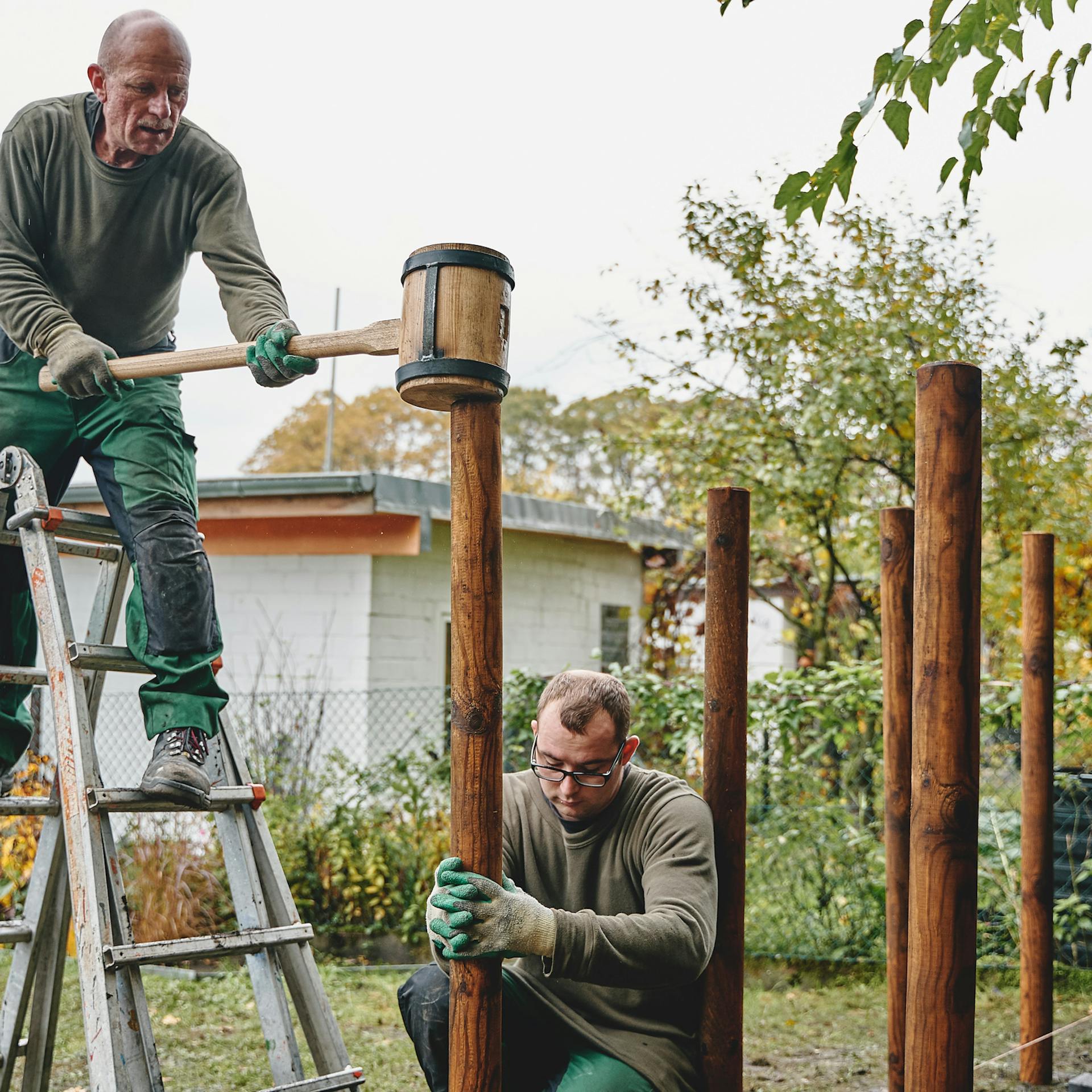 Männer schlagen Holzpflöcke in den Boden