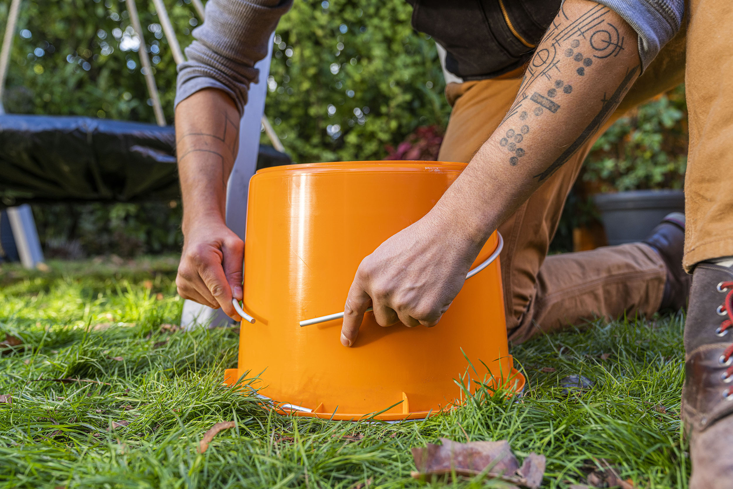 A mesterember hajlítja az alumíniumcsövet egy építési vödör segítségével. 