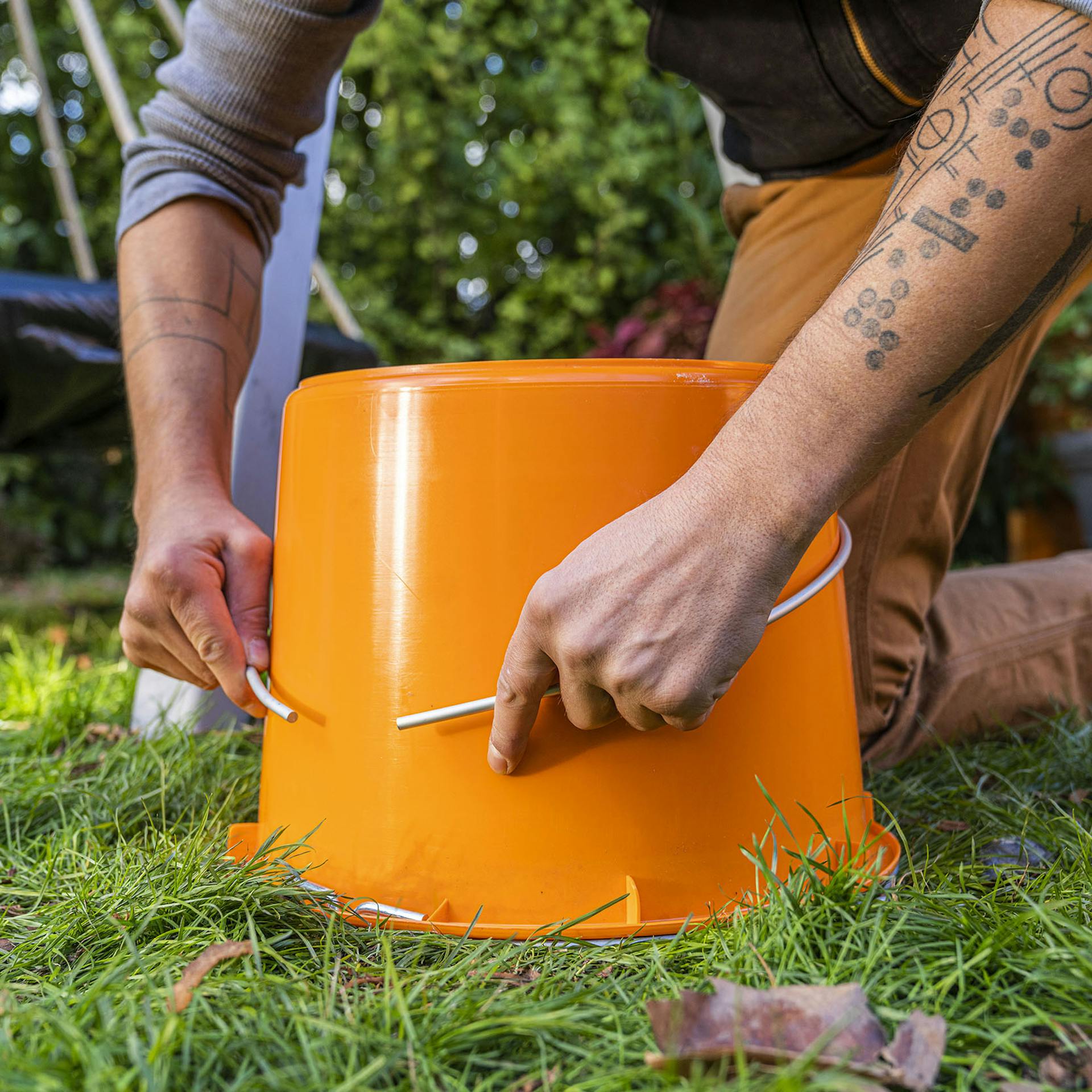 Handwerker biegt das Alurohr um einem Baukübel herum.