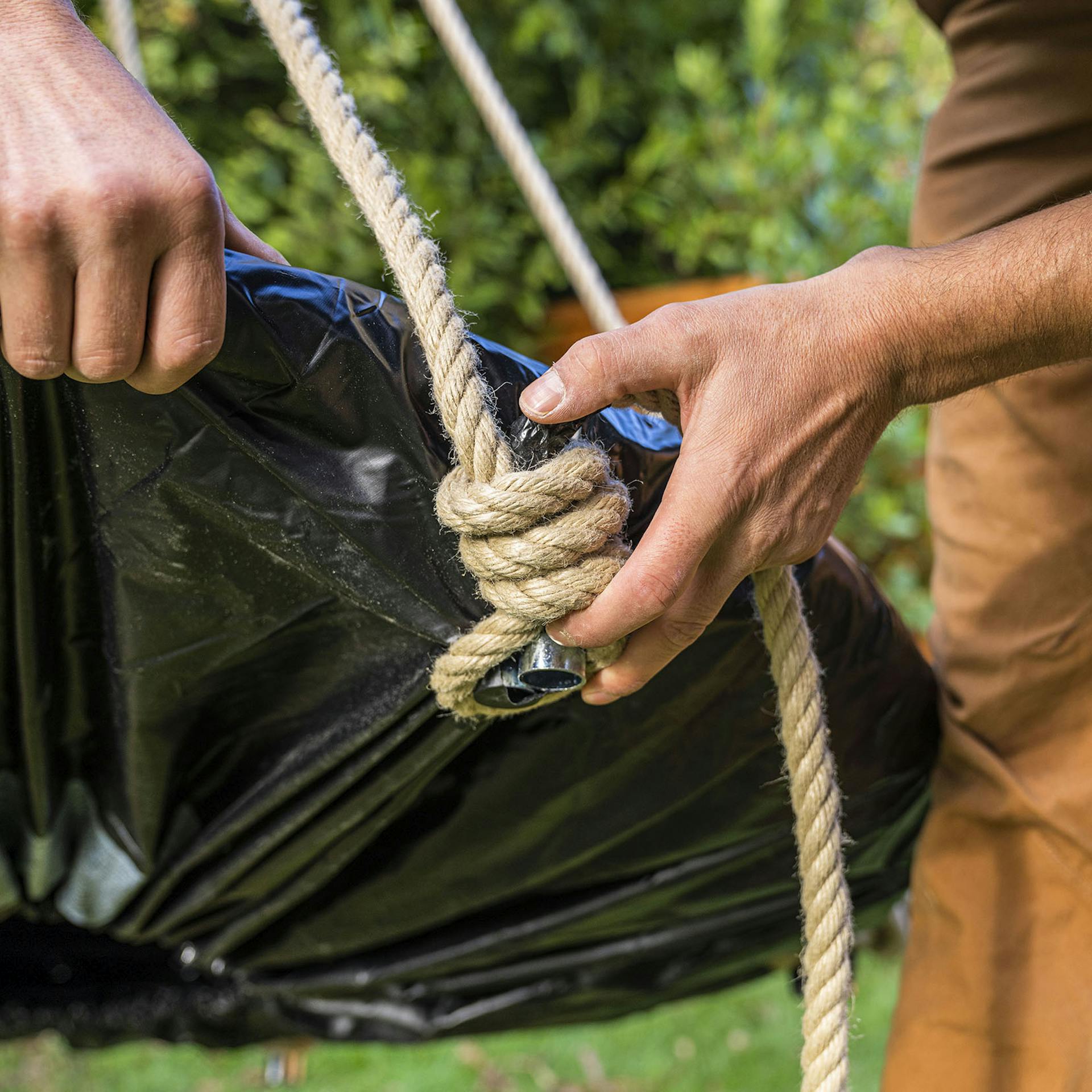 Handwerker legt einen Knoten rund um die Trampolinfüße.