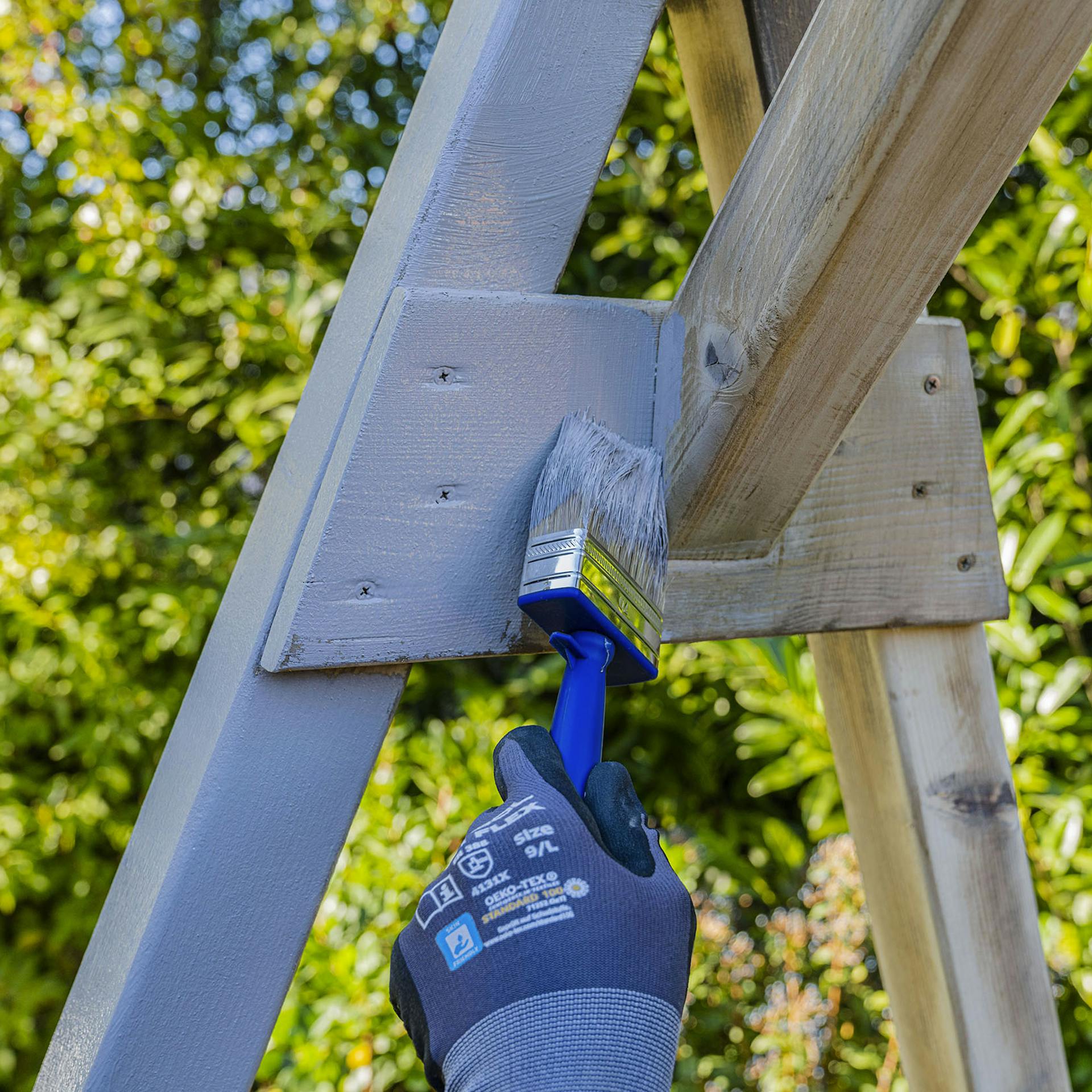 Handwerker streicht Gerüst mit Lackfarbe.