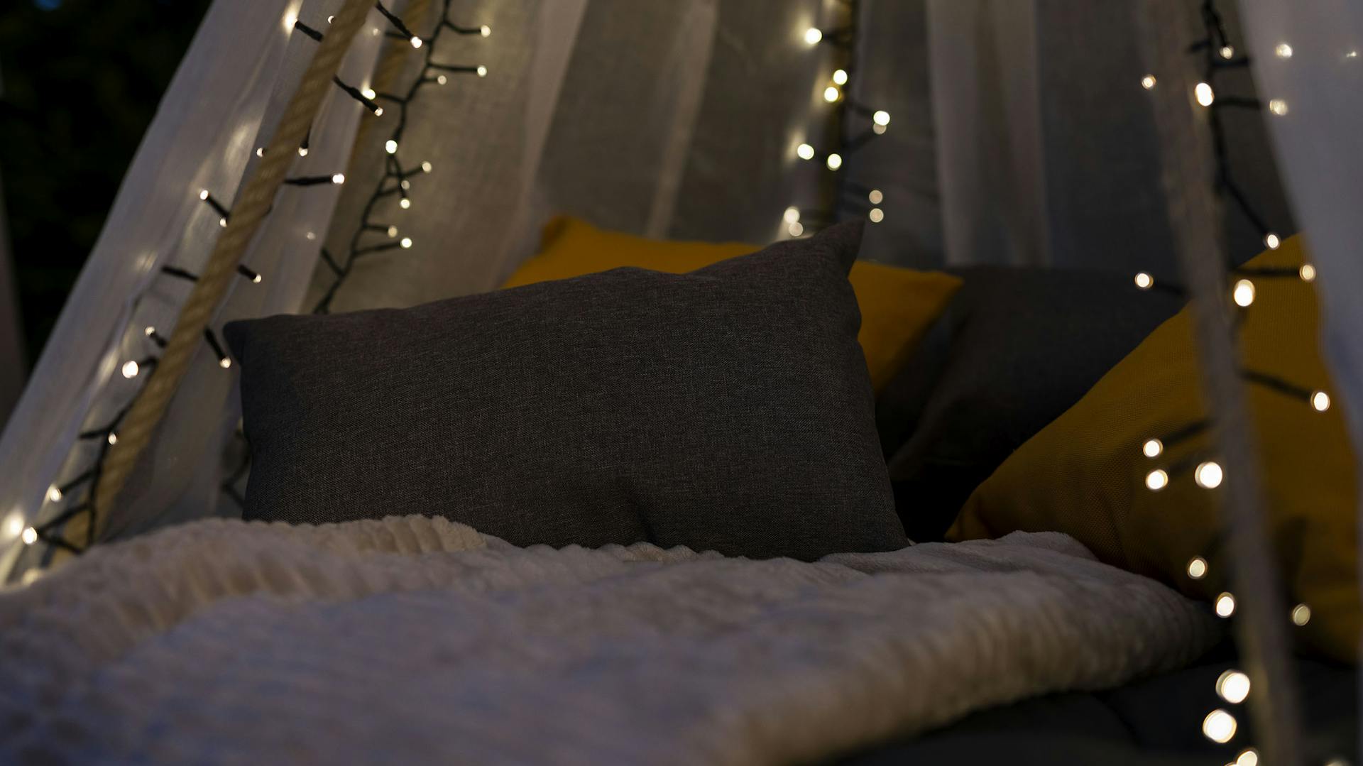 Nahaufnahme von dem Trampolin-Hängebett mit Polster, Decken und einer Lichterkette dekoriert.