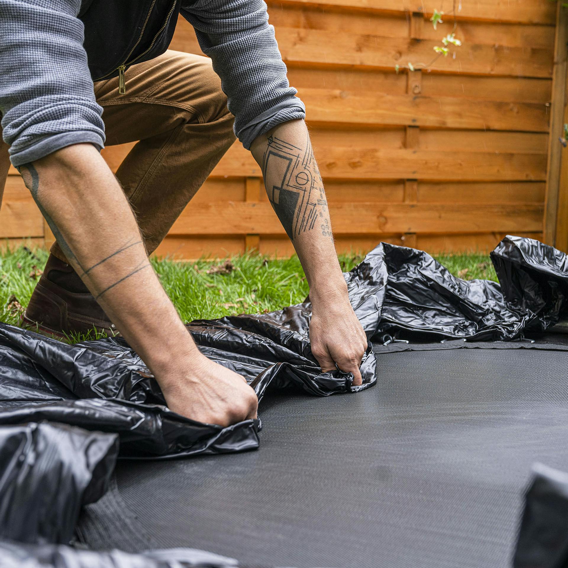 Handwerker zieht eine Poolabdeckung über den Trampolinboden.