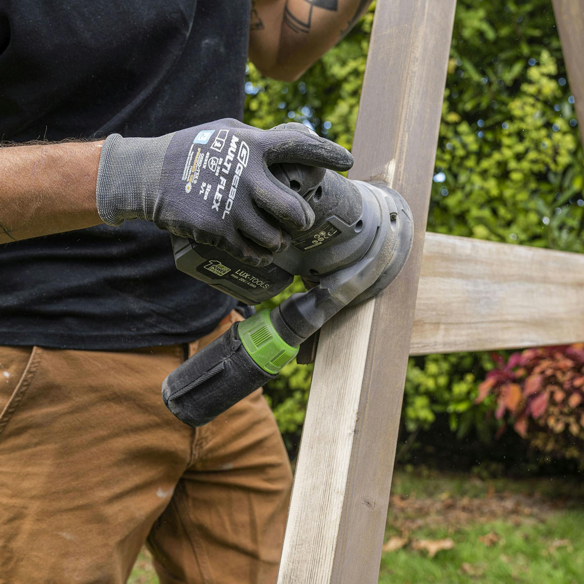 Handwerker schleift das Schaukelgerüst mit einem Akku-Multischleifer.