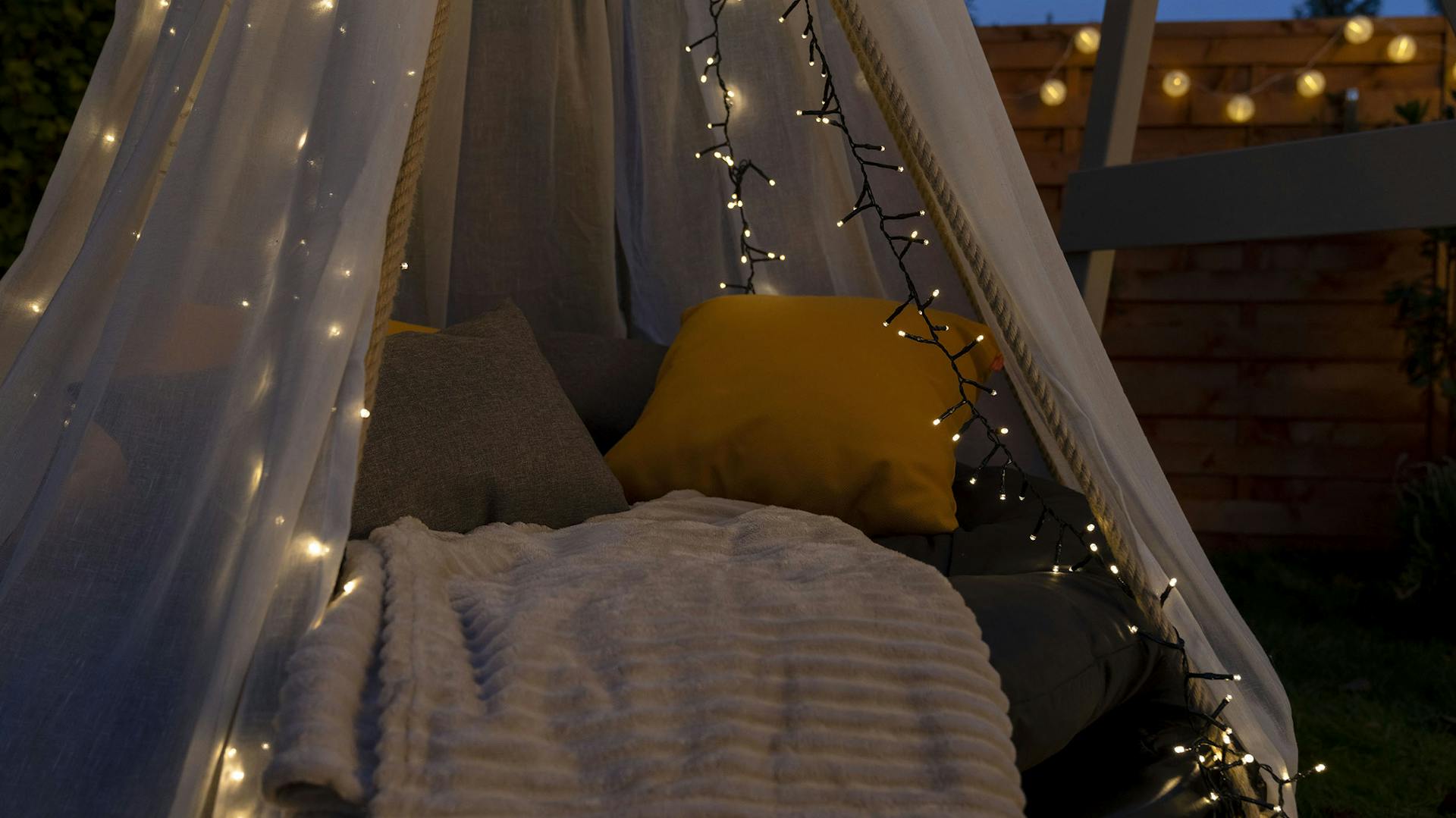 Nahaufnahme von dem Trampolin-Hängebett mit Polster, Decken und einer Lichterkette dekoriert.