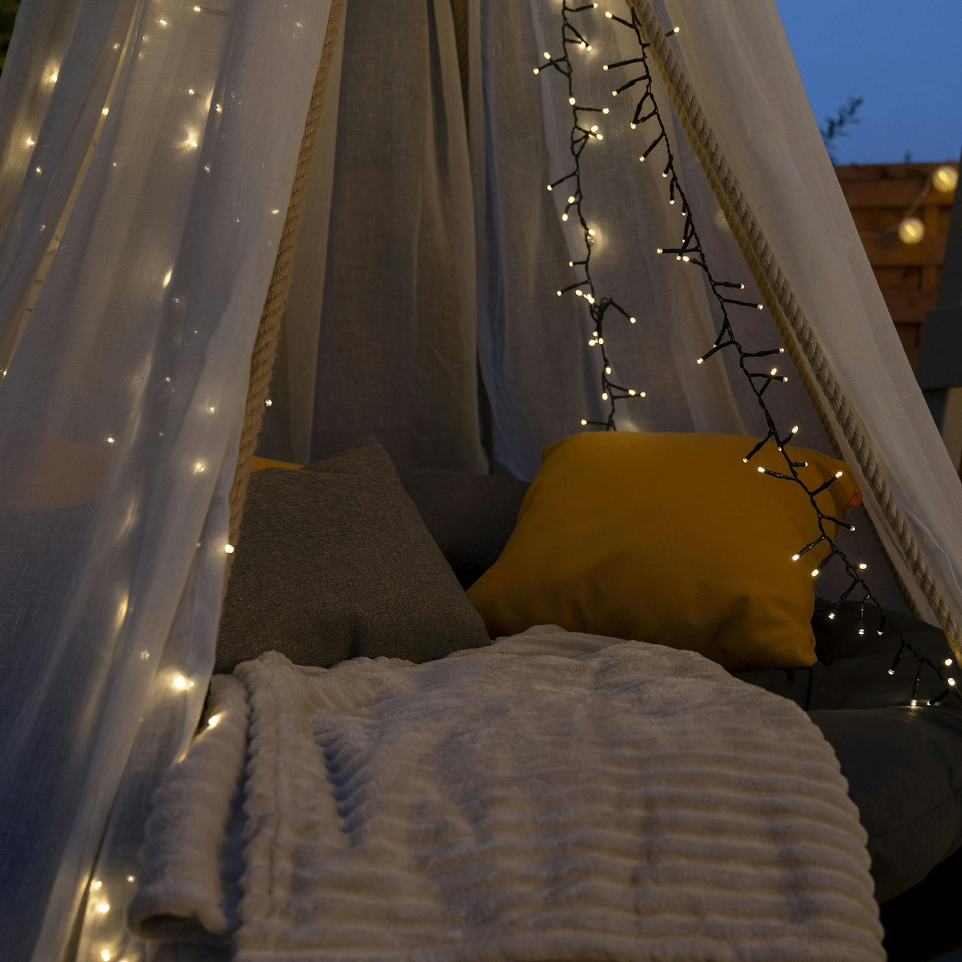 Nahaufnahme von dem Trampolin-Hängebett mit Polster, Decken und einer Lichterkette dekoriert.