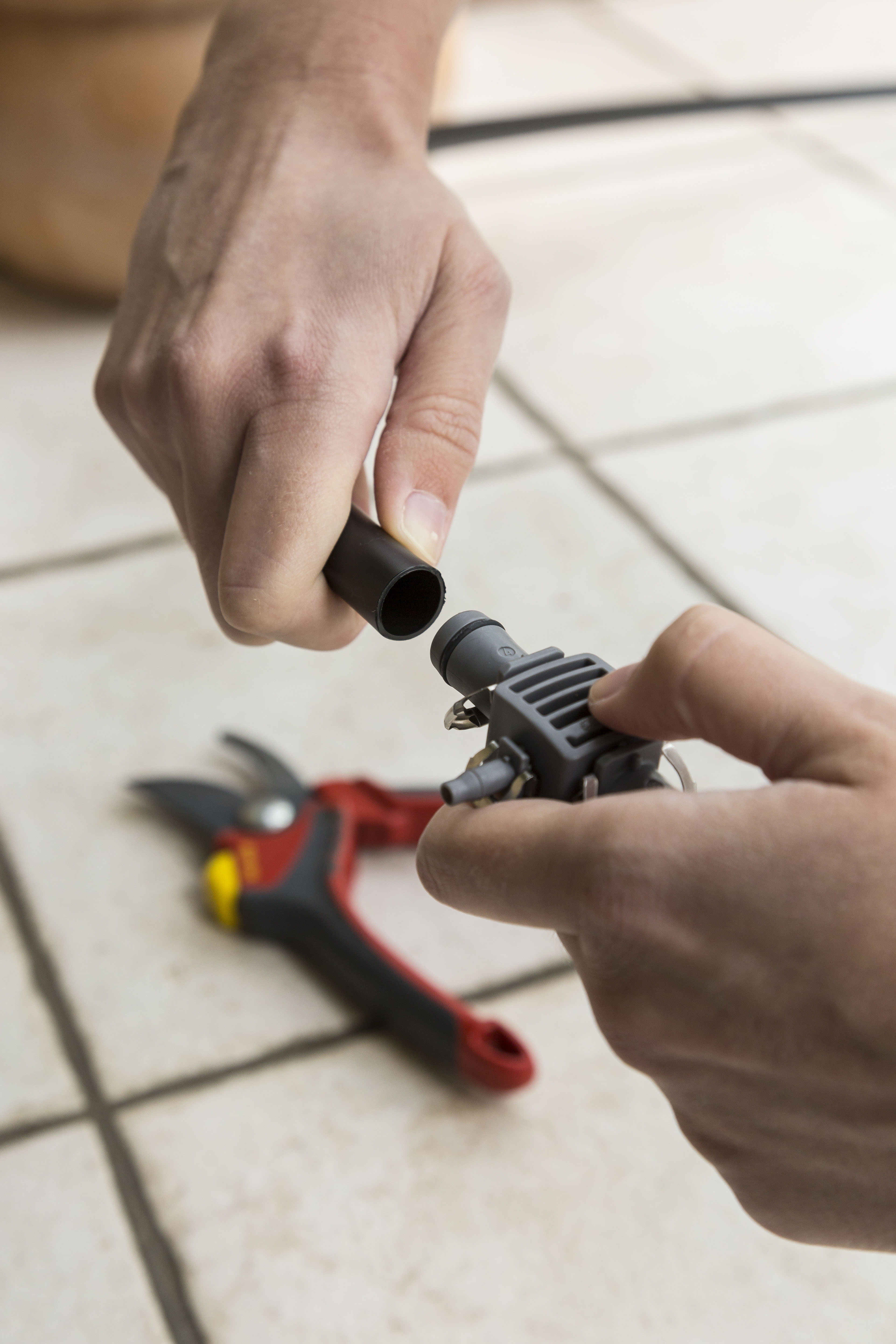 Una persona collega il tubo di un sistema di irrigazione a goccia con dei raccordi a T.