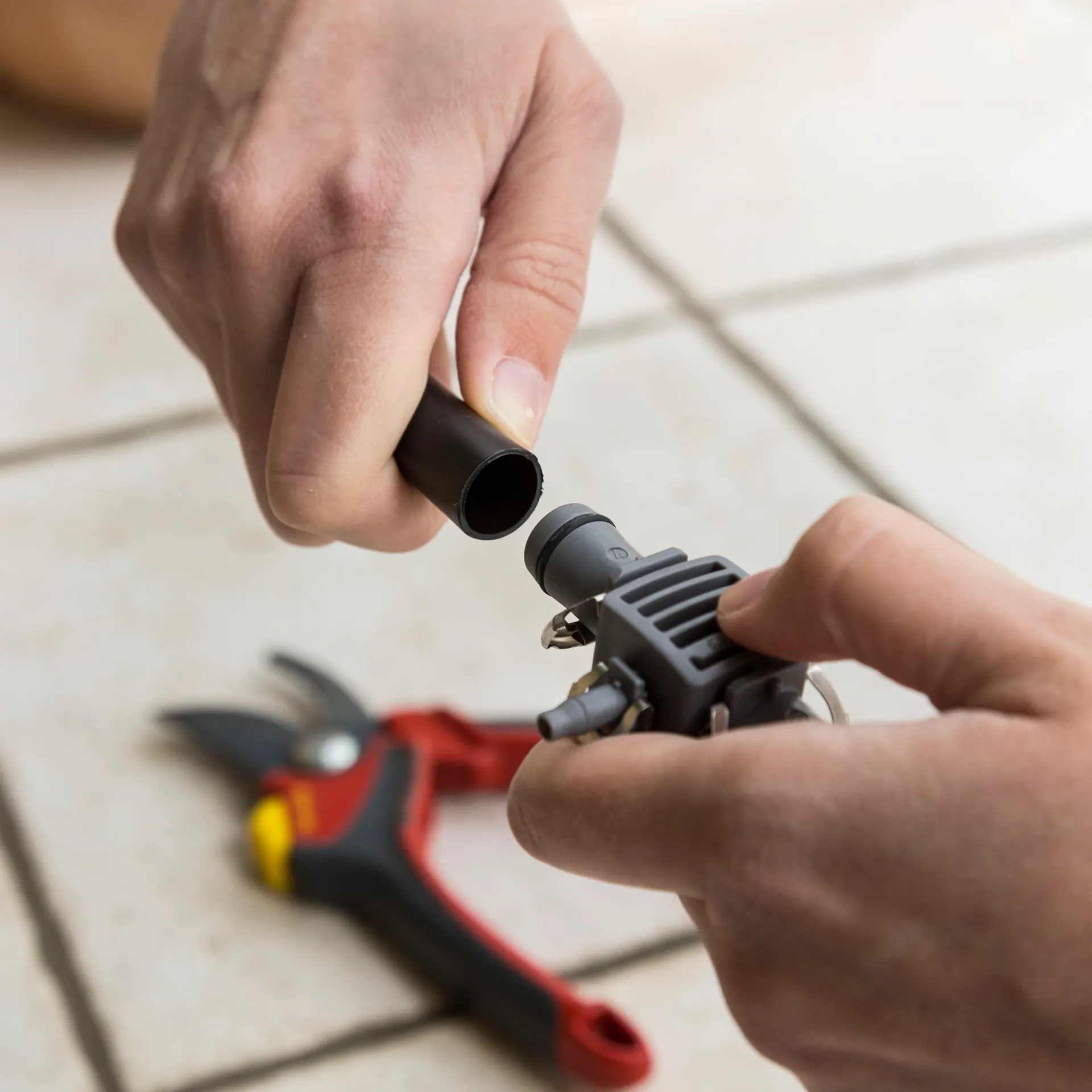 Una persona collega il tubo di un sistema di irrigazione a goccia con dei raccordi a T.