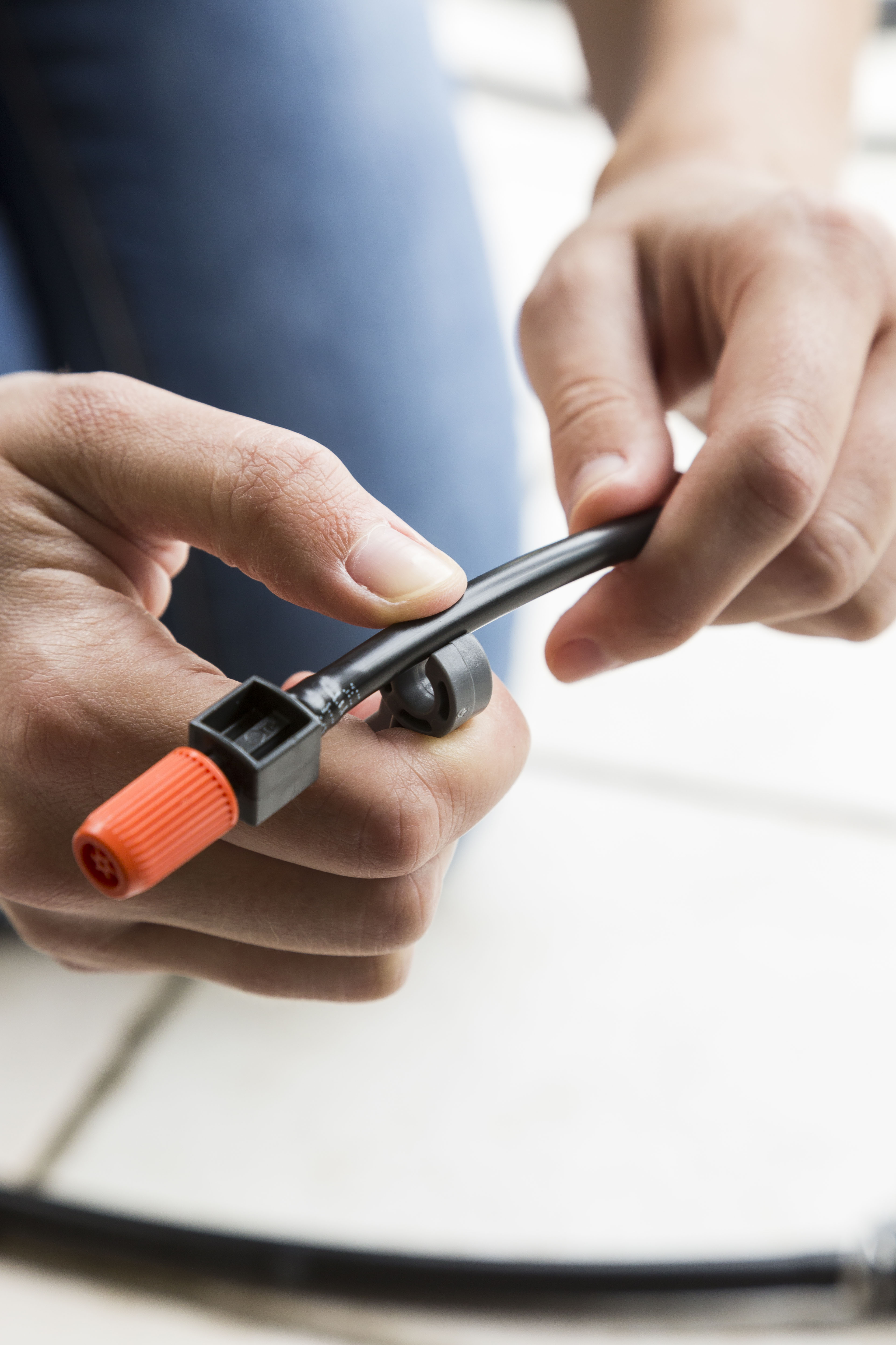 Con una clip, una persona attacca un supporto al tubo dell’irrigazione a goccia.