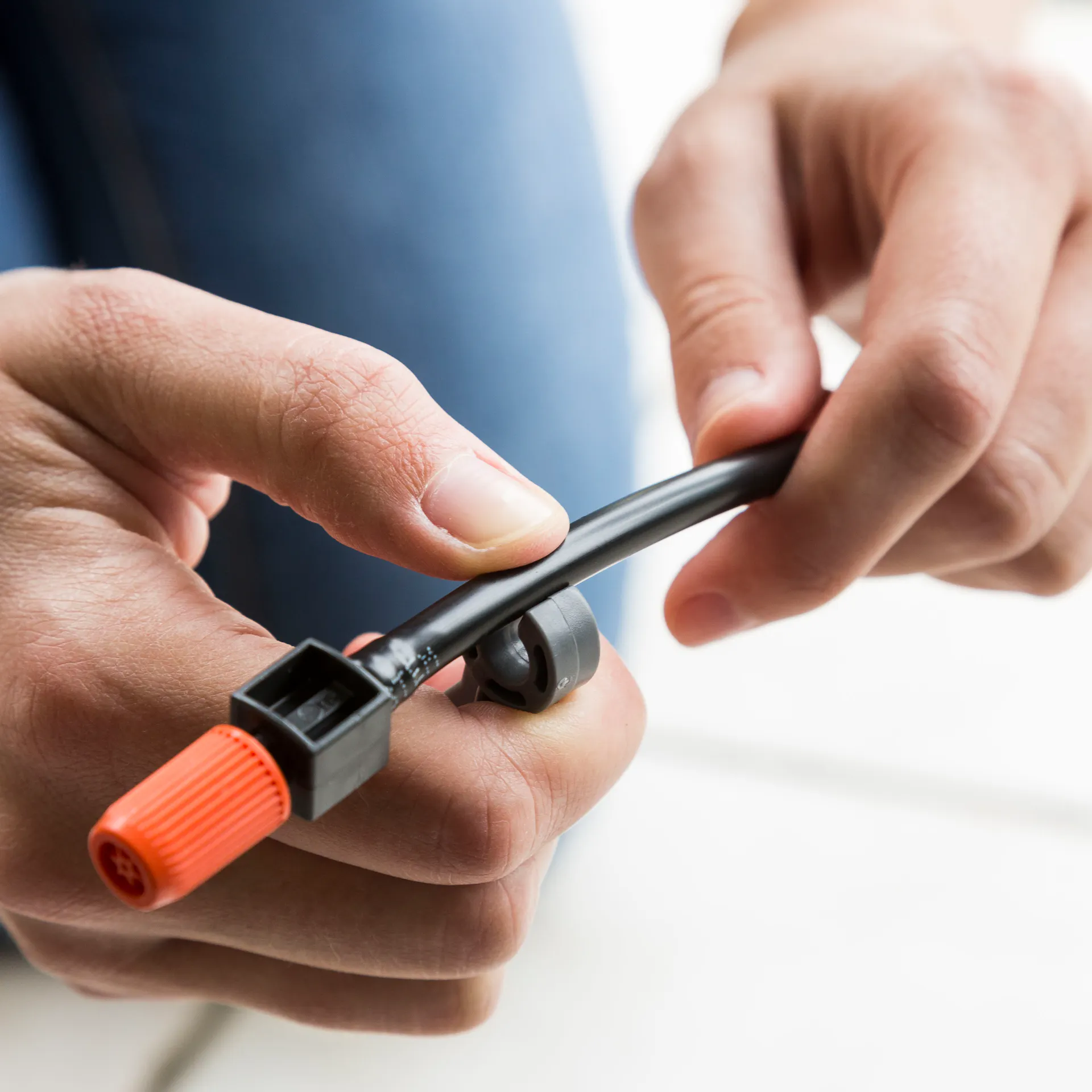 Con una clip, una persona attacca un supporto al tubo dell’irrigazione a goccia.