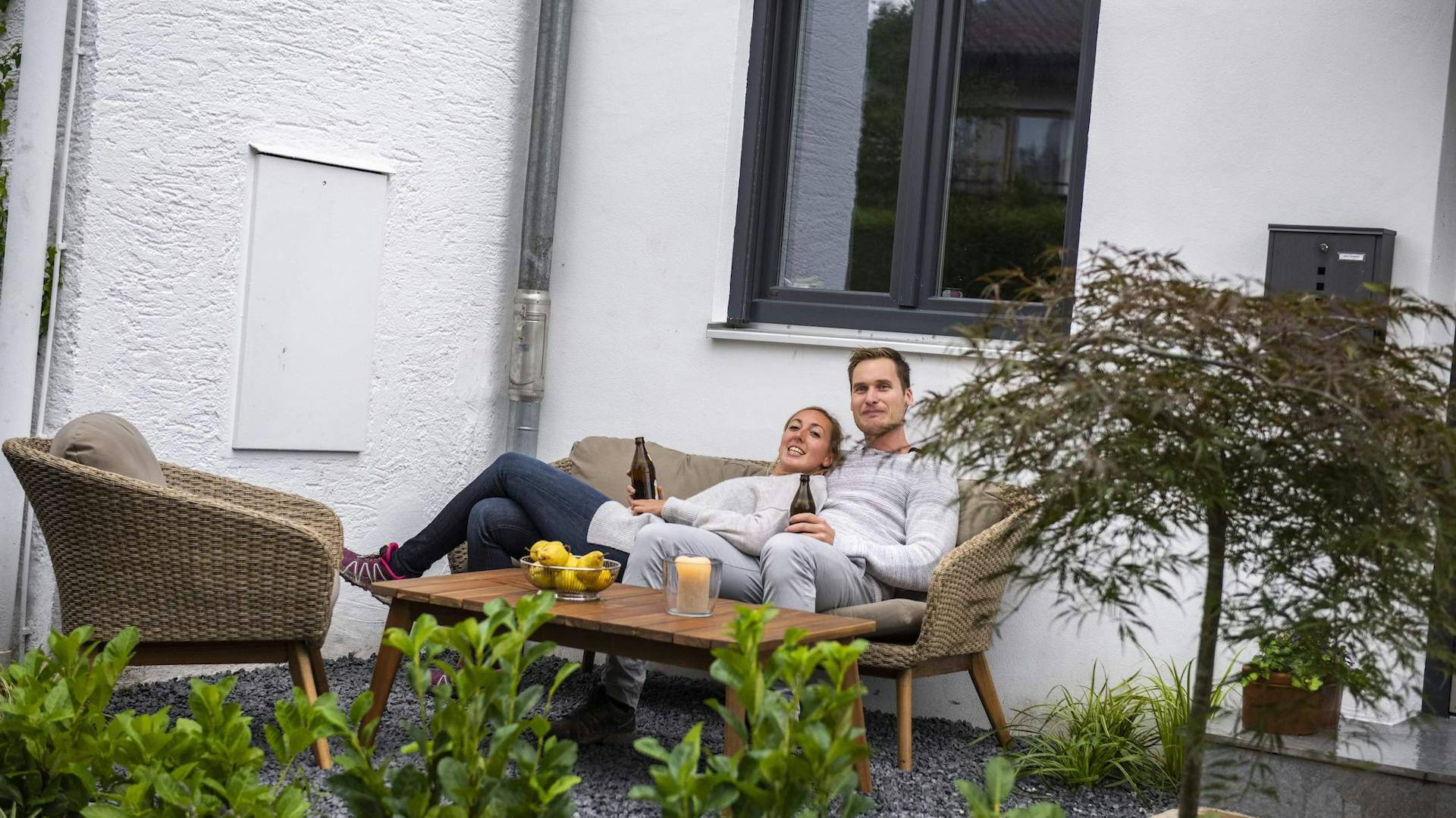 Mann und Frau sitzen im Vorgarten auf einer Lounge