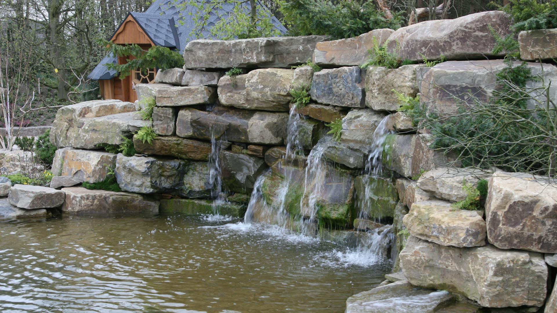 Wasserfall an einer Mauer und einem Gartenteich