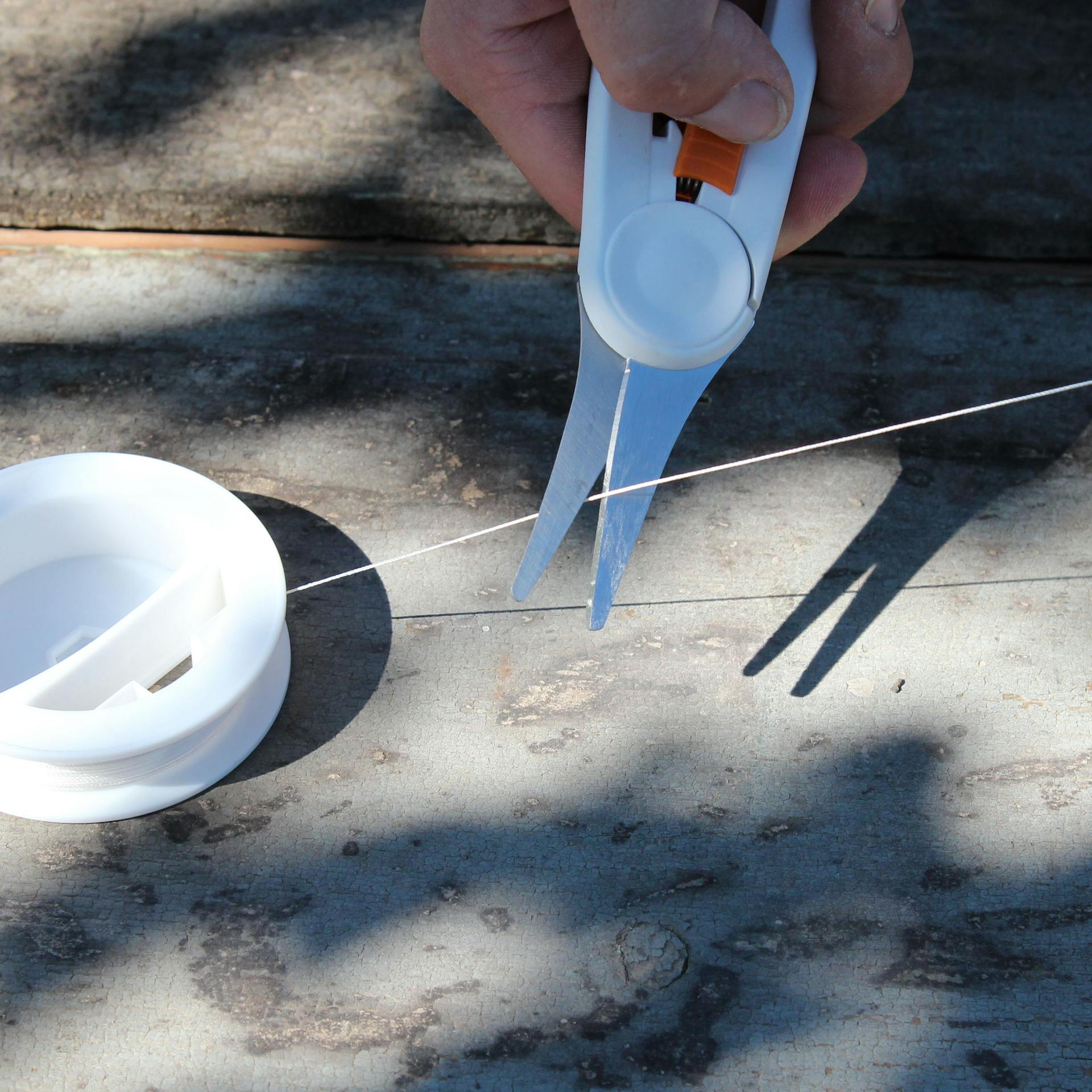 Heimwerker schneidet Nylonschnur mit Schere zu.