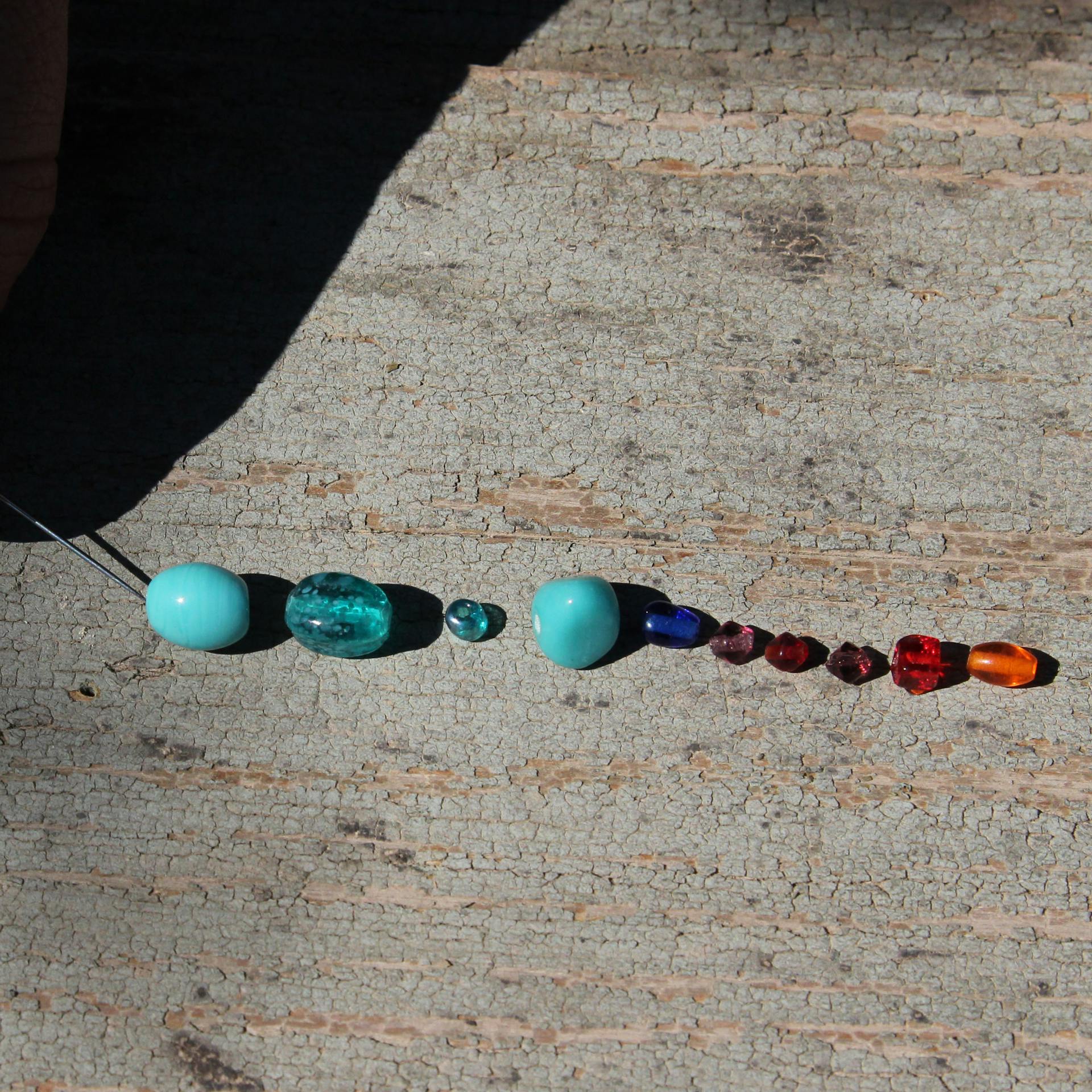 Heimwerker fädelt Perlen an Nylonschnur mit Nadel auf.