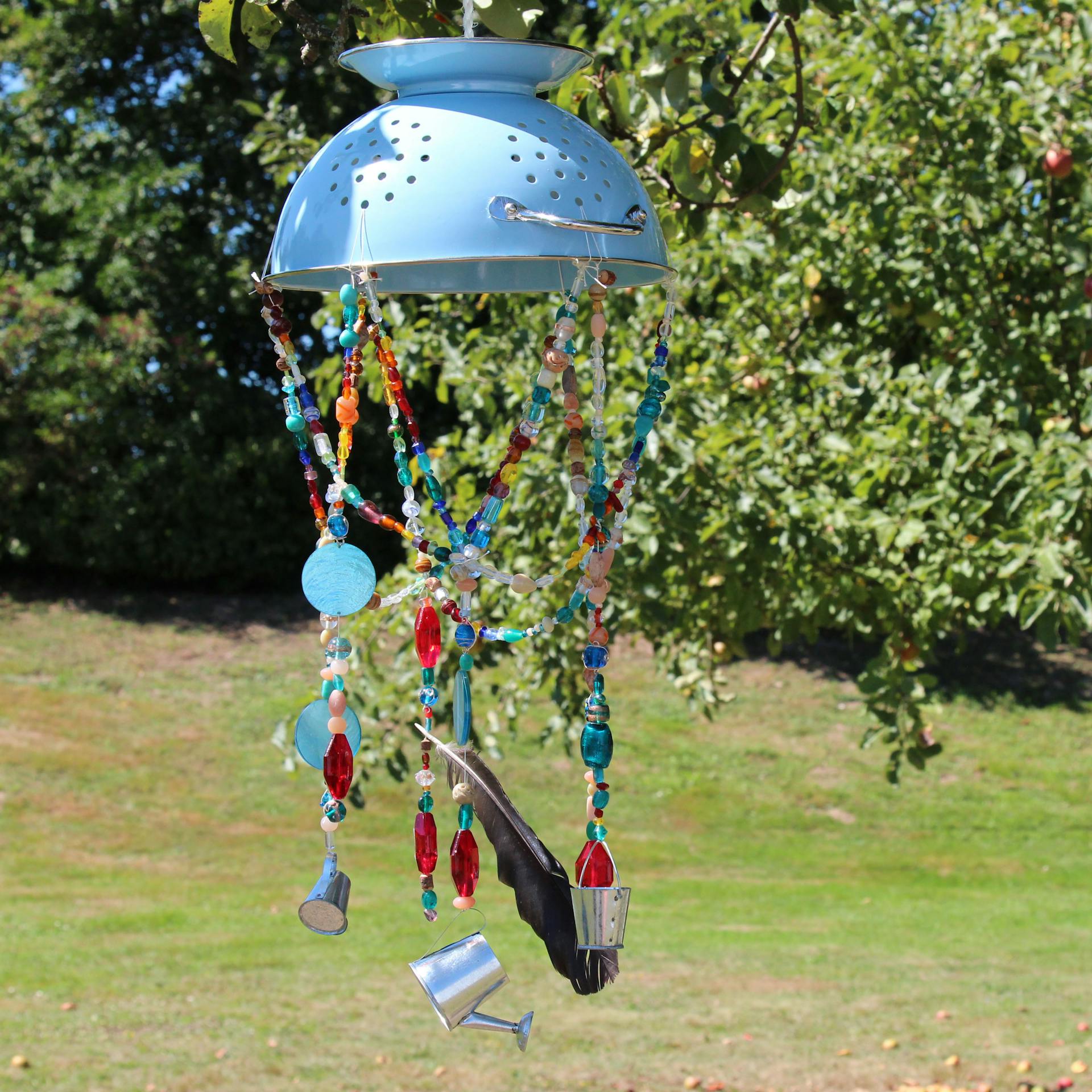 Bunt dekoriertes Windspiel am Baum im Garten