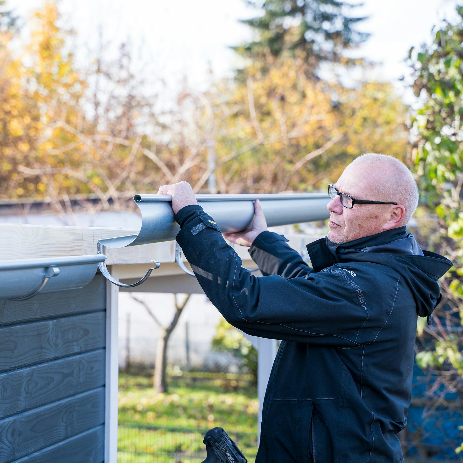 Egy ember ereszcsatornát helyez a tartóba.