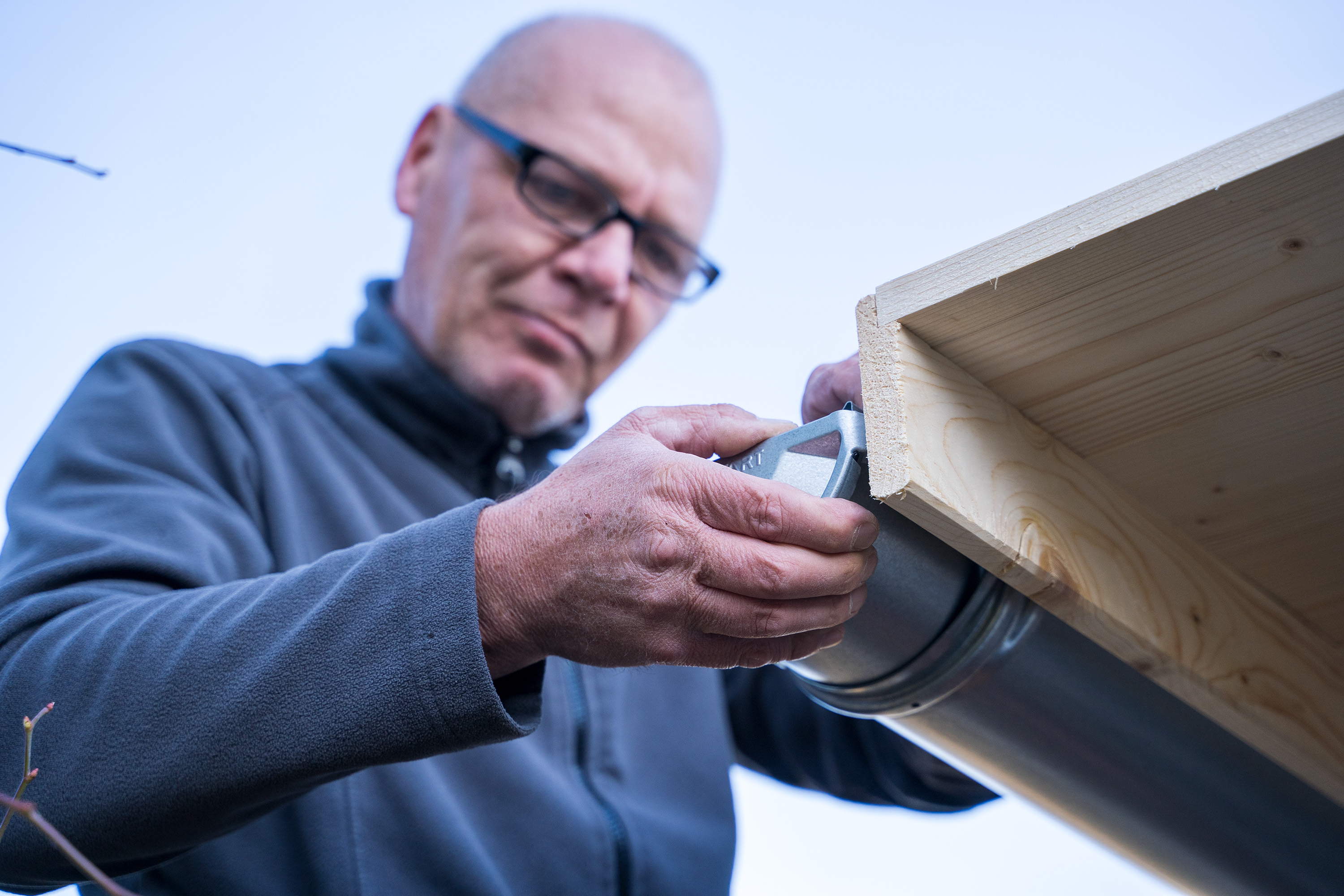 Egy ember rögzíti az ereszcsatorna végzáróját.