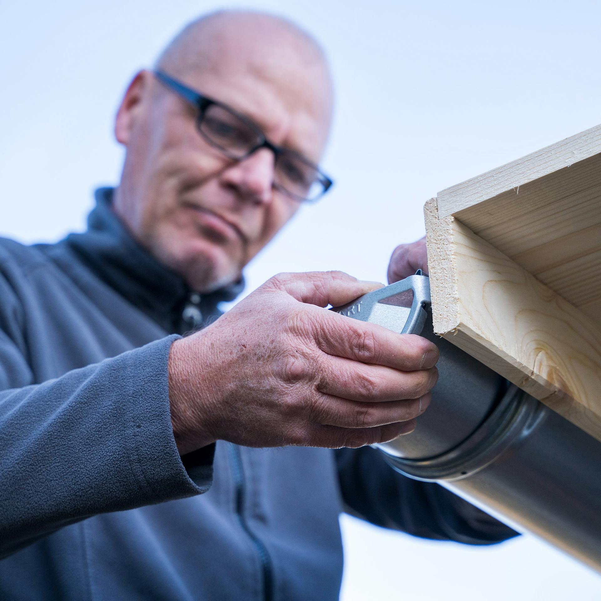 Egy ember rögzíti az ereszcsatorna végzáróját.