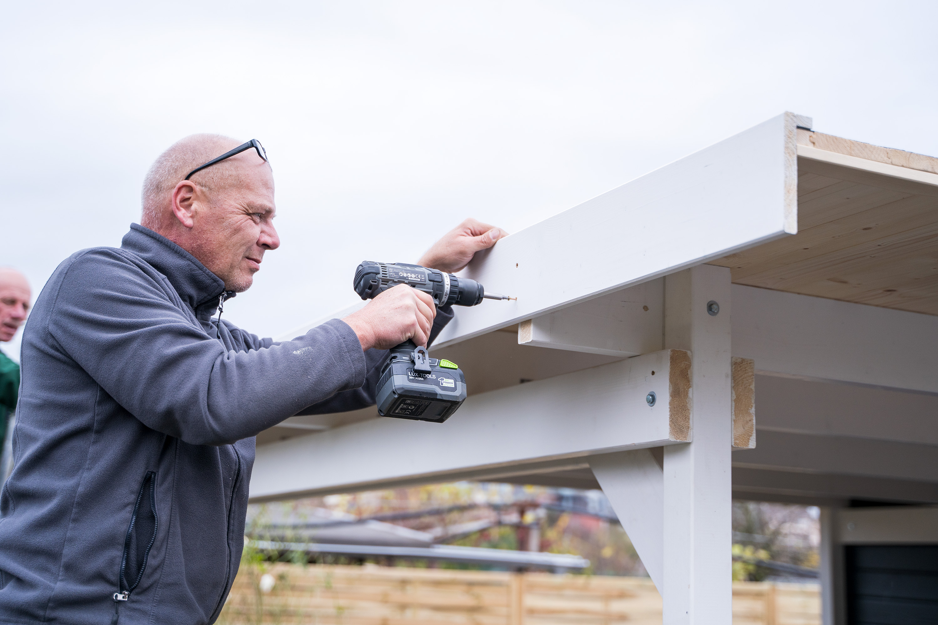 Egy ember fa takaróléceket szerel fel.