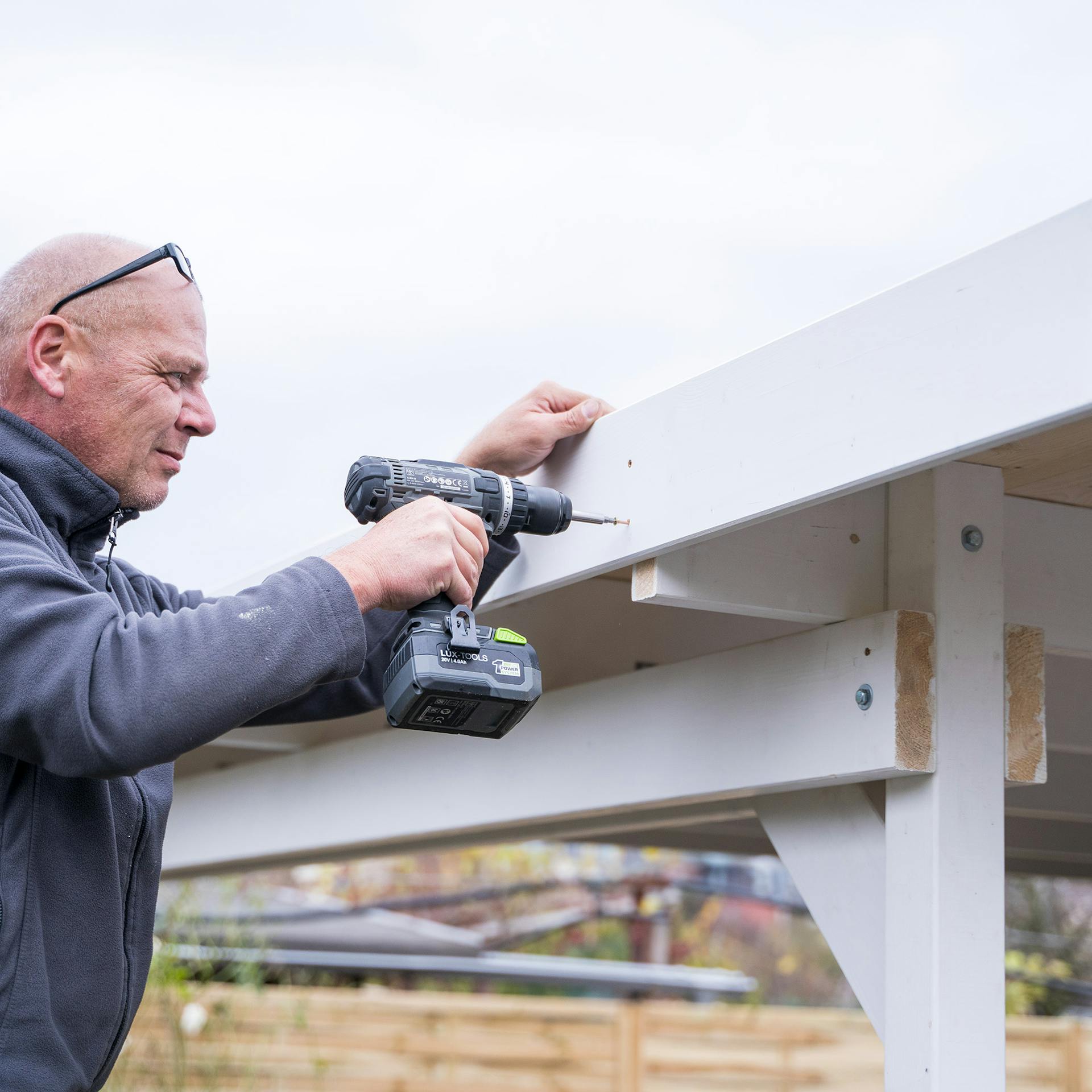 Egy ember fa takaróléceket szerel fel.