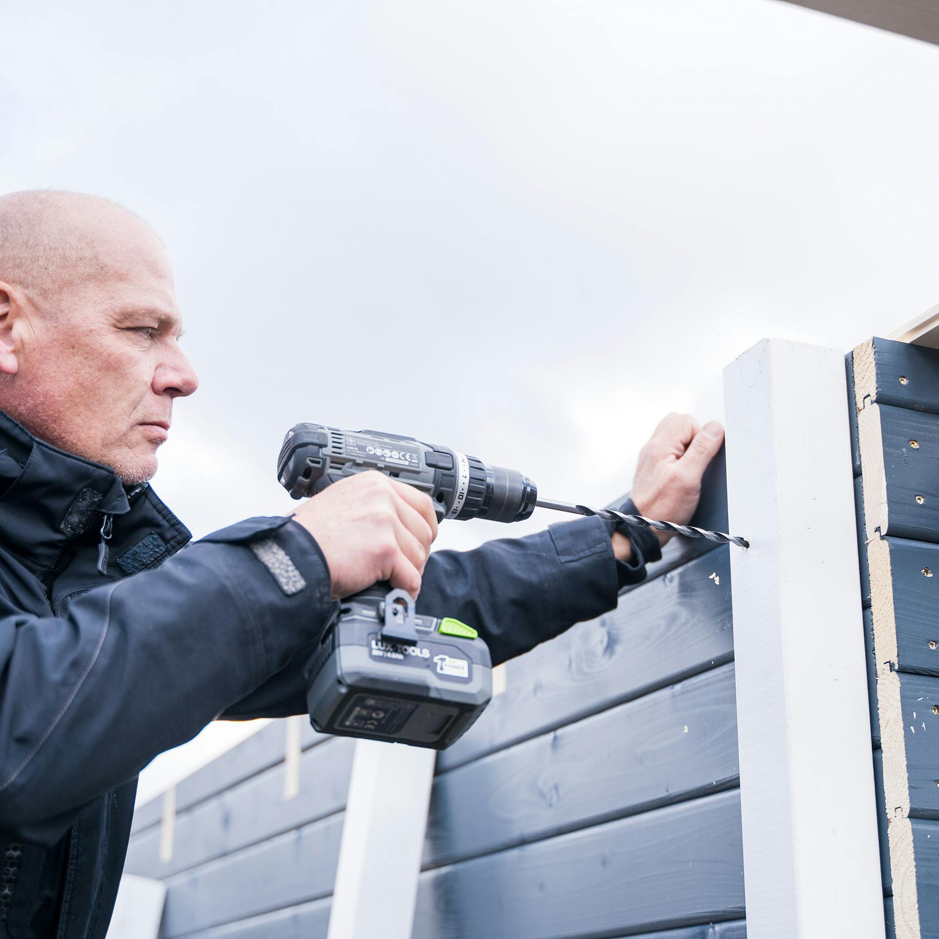 Egy ember előfuratokat készít az oldaltető sarokoszlopai számára.