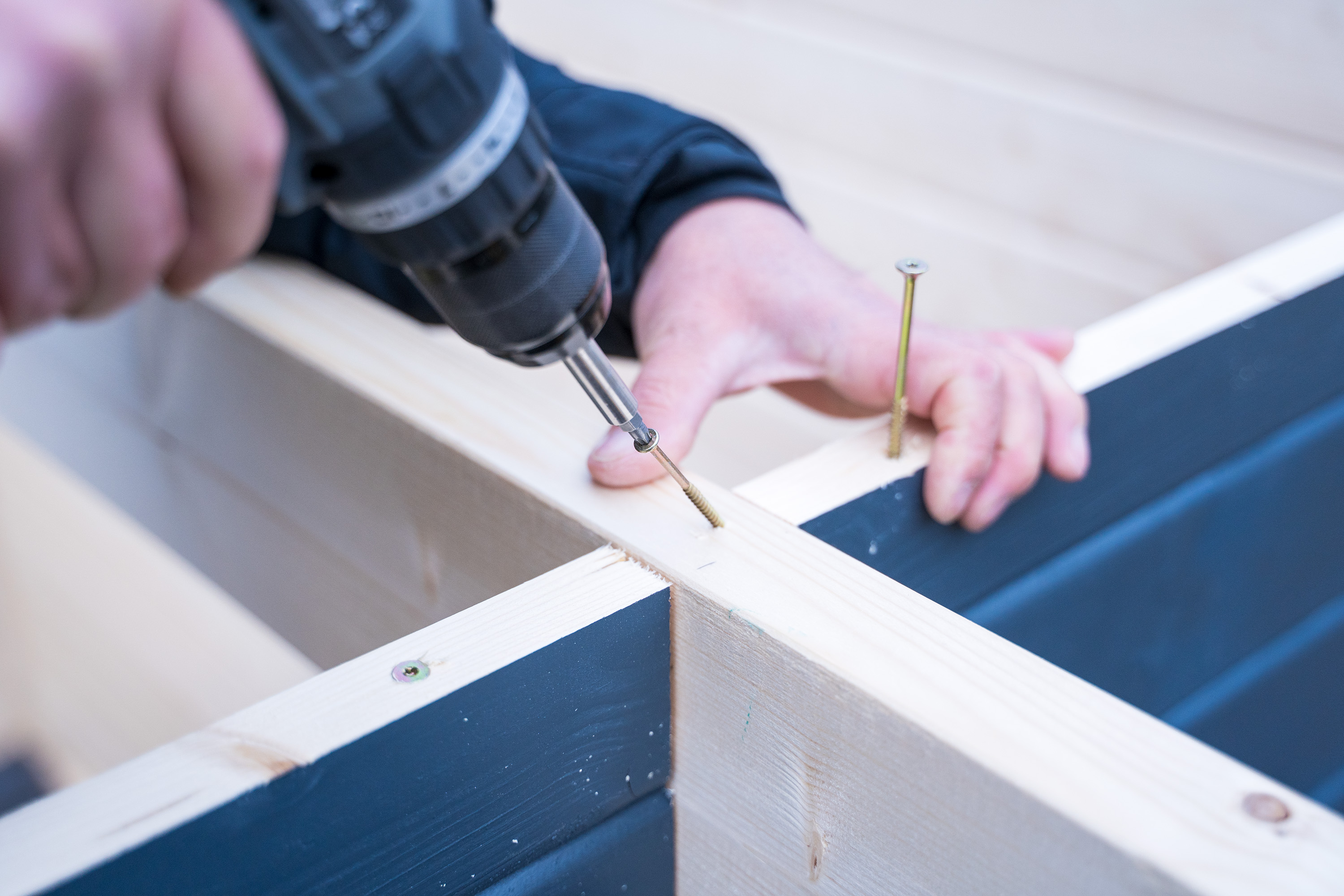 Egy már becsavarozott csavart újra kicsavaroznak, mielőtt rögzítik a tetőgerendát.