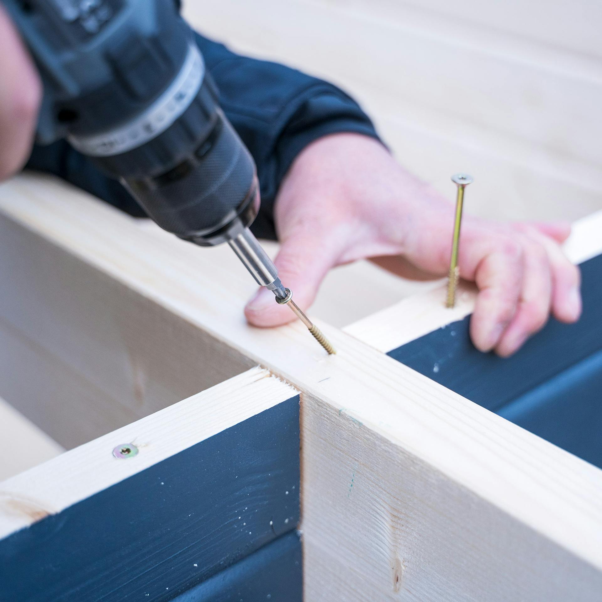 Egy már becsavarozott csavart újra kicsavaroznak, mielőtt rögzítik a tetőgerendát.