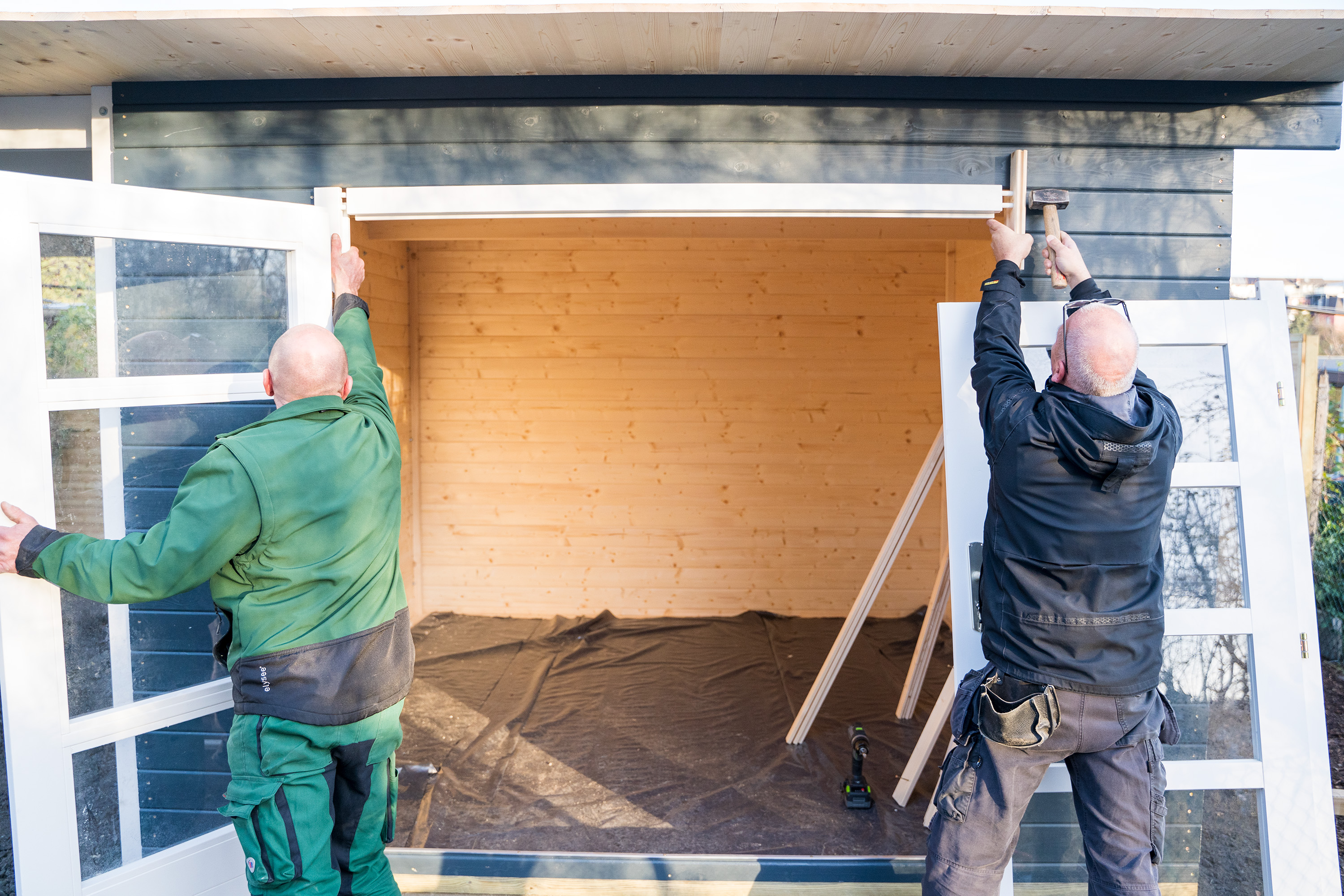 Két ember fakalapáccsal rögzíti a szemöldökfát.