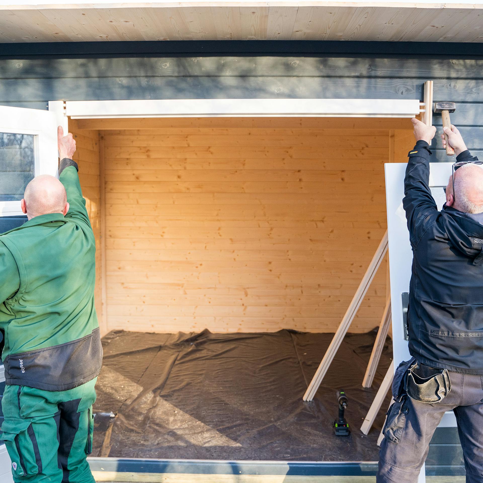 Két ember fakalapáccsal rögzíti a szemöldökfát.