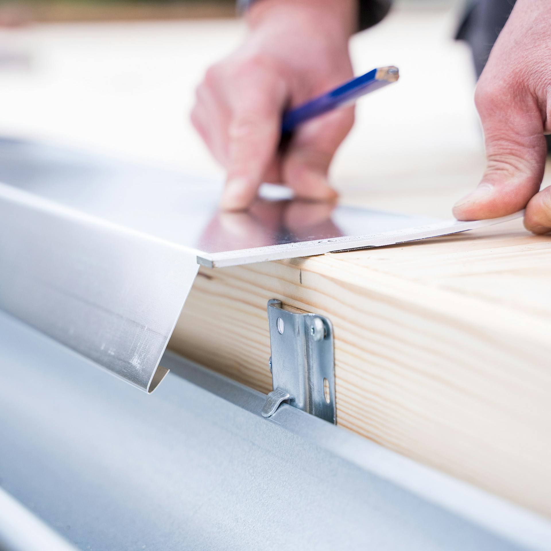 Egy ember ereszlemezt szerel fel egy tetőre.