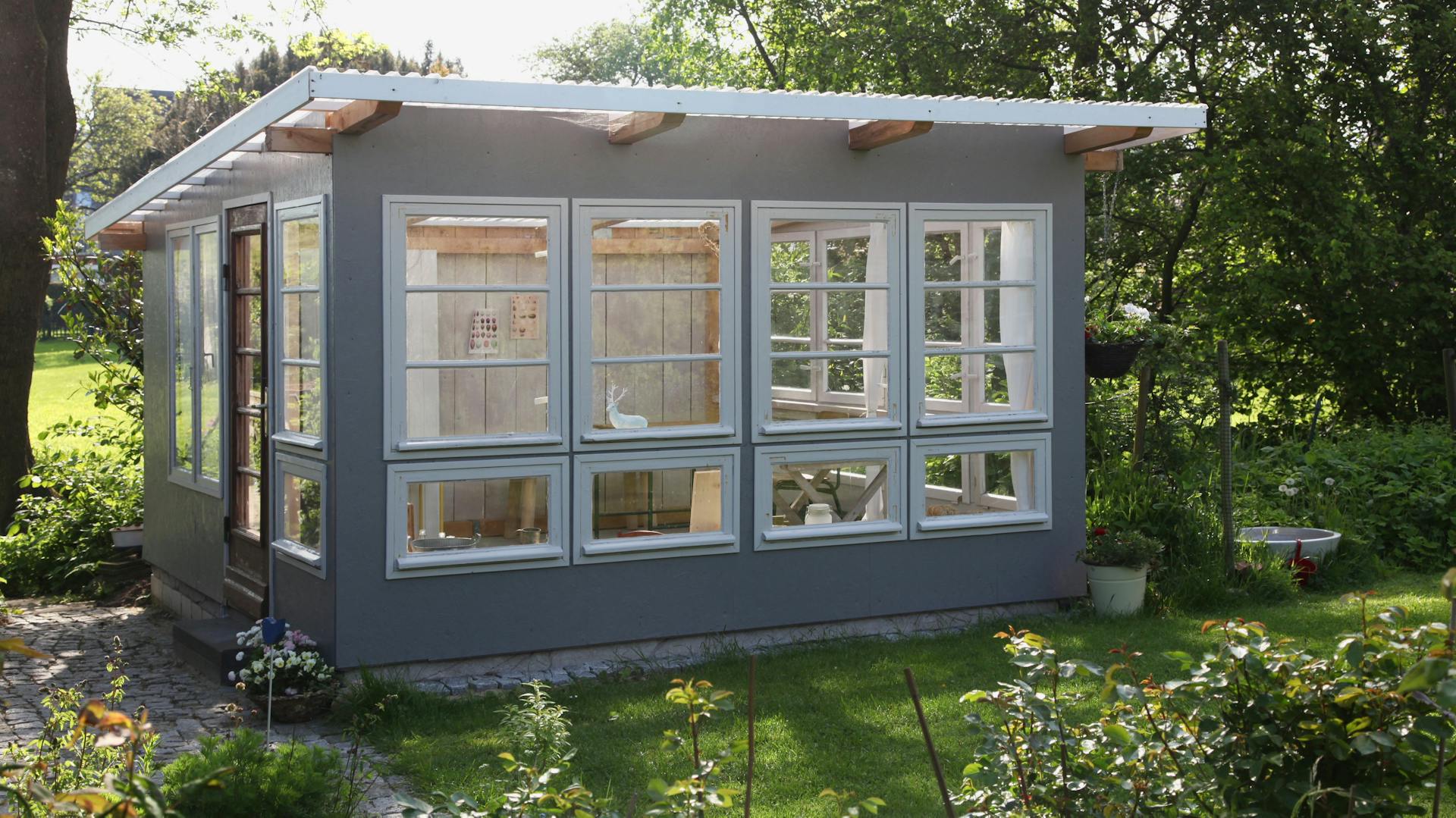 Graues Gartenhaus im Garten.