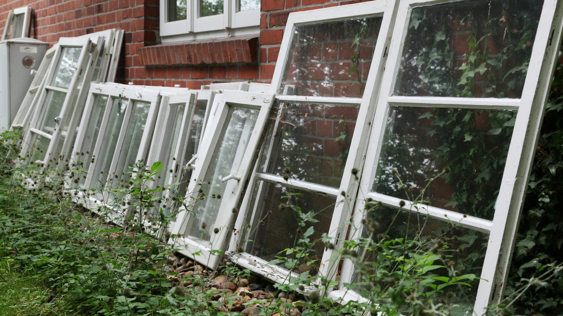 Régi ablakok egy téglafalnak támasztva.