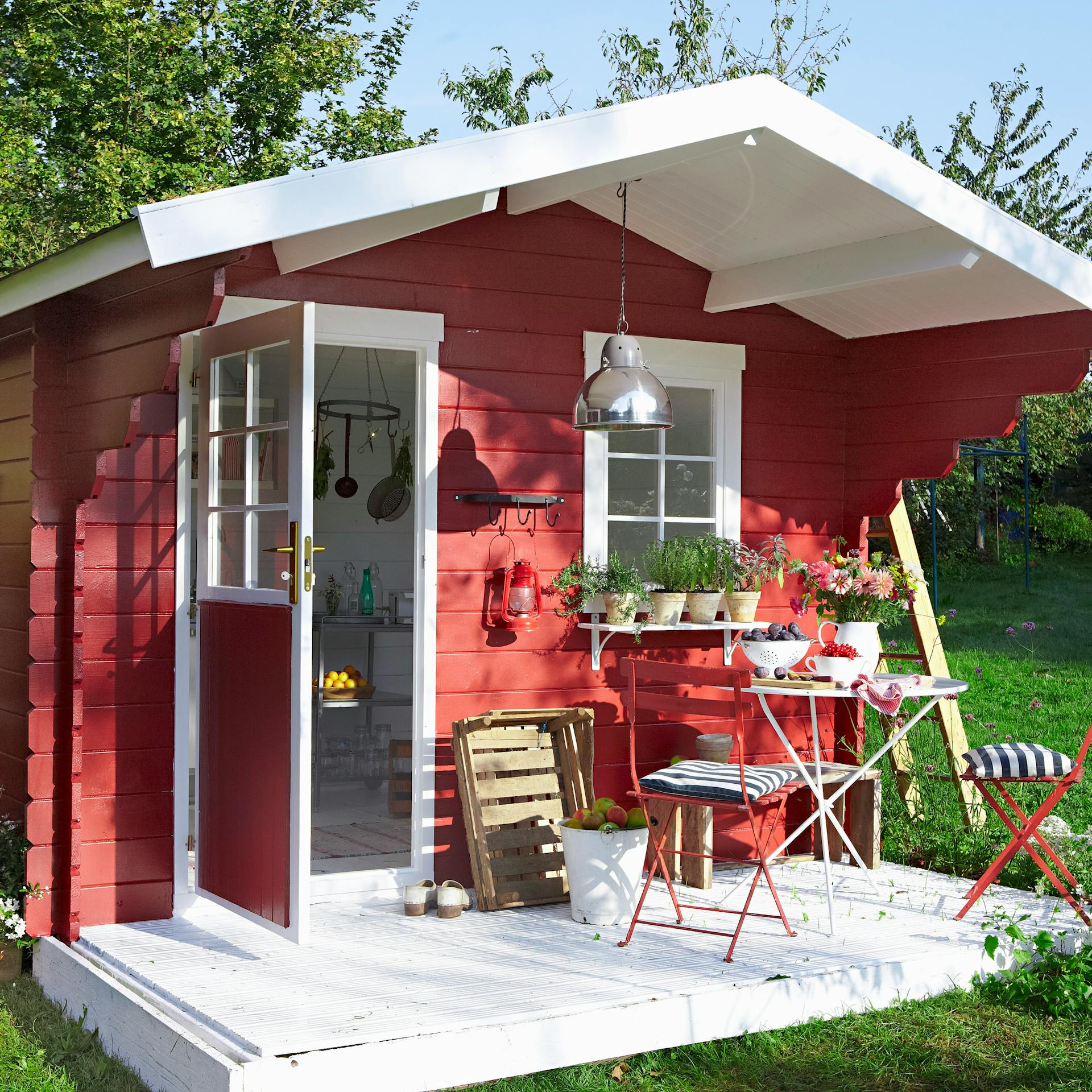 Piros kerti ház skandináv stílusban kerti bútorokkal és növényekkel